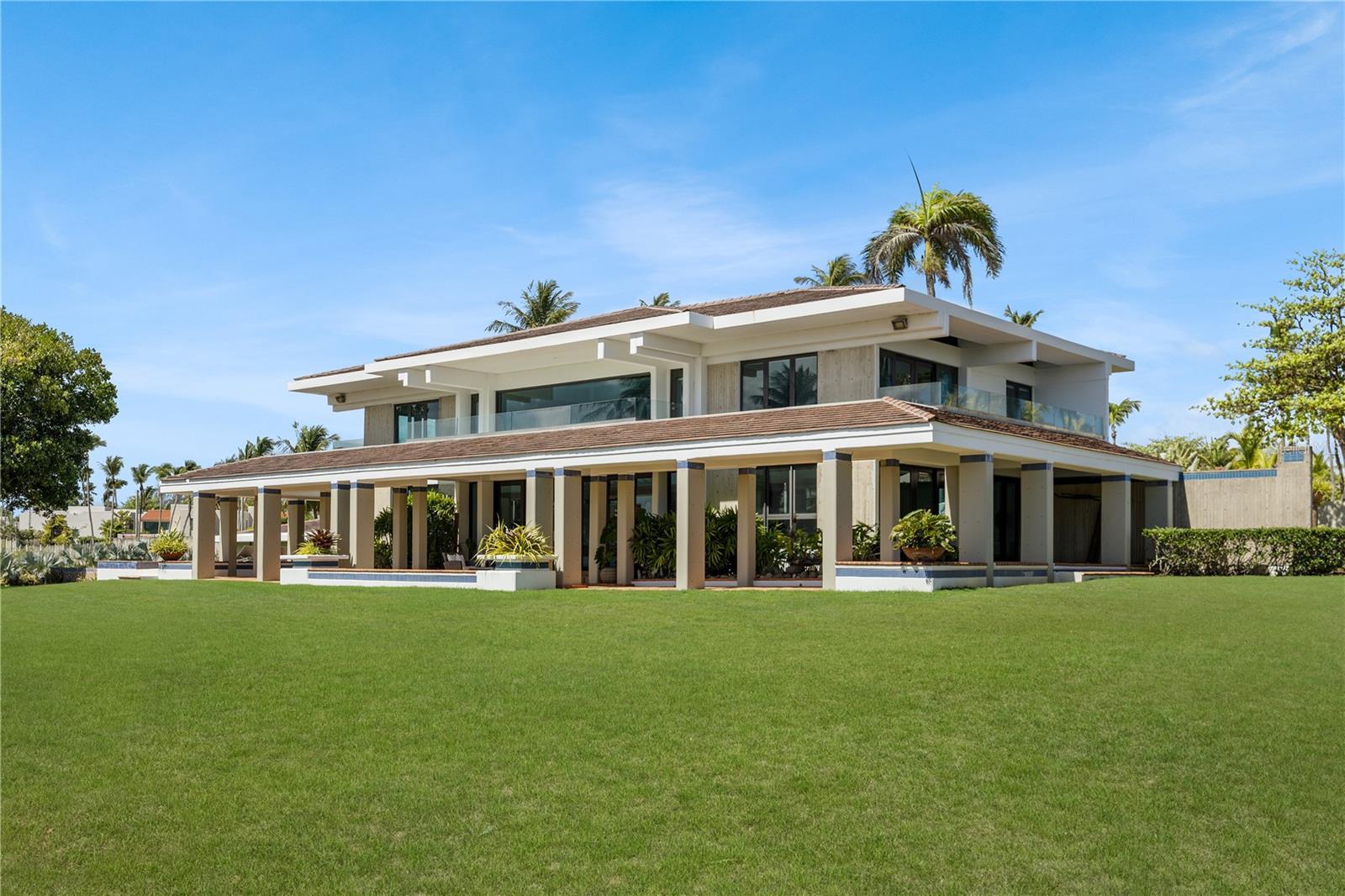 Introducing The Redonda Estate. A remarkable private residence set on more than three acres overlooking the Mata Redonda Lagoon and the West Golf Course of Dorado Beach Resort. Defined by its scale, privacy, and privileged setting, the property features a private pond, proximity to the beach, and extensive grounds that create a remarkable feeling of privacy and openness within one of Dorado’s most coveted residential enclaves. Designed as a private retreat yet equally suited to grand-scale entertaining, the property encompasses a turn-key main residence of more than 9,000 square feet, including 4,865 square feet of interior living space, complemented by a separate 1,635-square-foot guest house. Beyond its existing residences, the extraordinary acreage and Residential-Touristic zoning create an uncommon range of possibilities – from a multigenerational family compound or the addition of further residential components to the creation of a private resort-like environment with recreational courts, gardens, and expansive outdoor amenities. Originally designed by Thomas S. Marvel, known for championing tropical modernism in Puerto Rico and the Caribbean, The Redonda Estate was completely renovated in 2016. The main residence balances contemporary refinement with an effortless, highly livable design. Interiors open naturally to the surrounding terraces and gardens, allowing the beauty of the lagoon, golf course, and tropical landscape to become part of everyday life. The chef’s kitchen features custom Cucine Lube Italian cabinetry, elegant quartz countertops, a generous central island designed for gathering, and a beautifully appointed butler’s pantry. Multiple living and entertaining spaces, including two living rooms and a separate family room, provide flexibility for both intimate moments and larger gatherings. The main residence offers four bedrooms plus a guest suite, four full bathrooms, and a half bathroom. The primary suite is conceived as a private sanctuary, opening onto a generous terrace overlooking the lagoon and golf course. Its generous primary bath features a walk-in shower and spa-inspired finishes. Outdoor living is central to the experience. Approximately 4,475 square feet of covered and uncovered terraces, balconies, and decks extend the living spaces into the landscape, creating distinct settings for dining, lounging, entertaining, and simply taking in the panoramic surroundings. The infinity-edge pool, meticulously landscaped gardens, and sprawling lawns complete the setting, creating an atmosphere of privacy and tranquility.The separate guest house provides two guest rooms, one full bathroom and a half bathroom, together with a two-car garage, mechanical rooms, and additional storage, offering privacy and independence for extended family, guests, or staff. Electrolux and BOSCH premium appliances, refined finishes, a water cistern, diesel backup generator, and meticulous attention to detail further enhance the property’s functionality and resilience. Rarely does an estate of this scale, versatility, and distinction become available in Dorado. With more than three acres, a private pond, commanding lagoon and golf course views, and proximity to the beach, this is not simply a home – it is an exceptional legacy property and a truly extraordinary private estate.