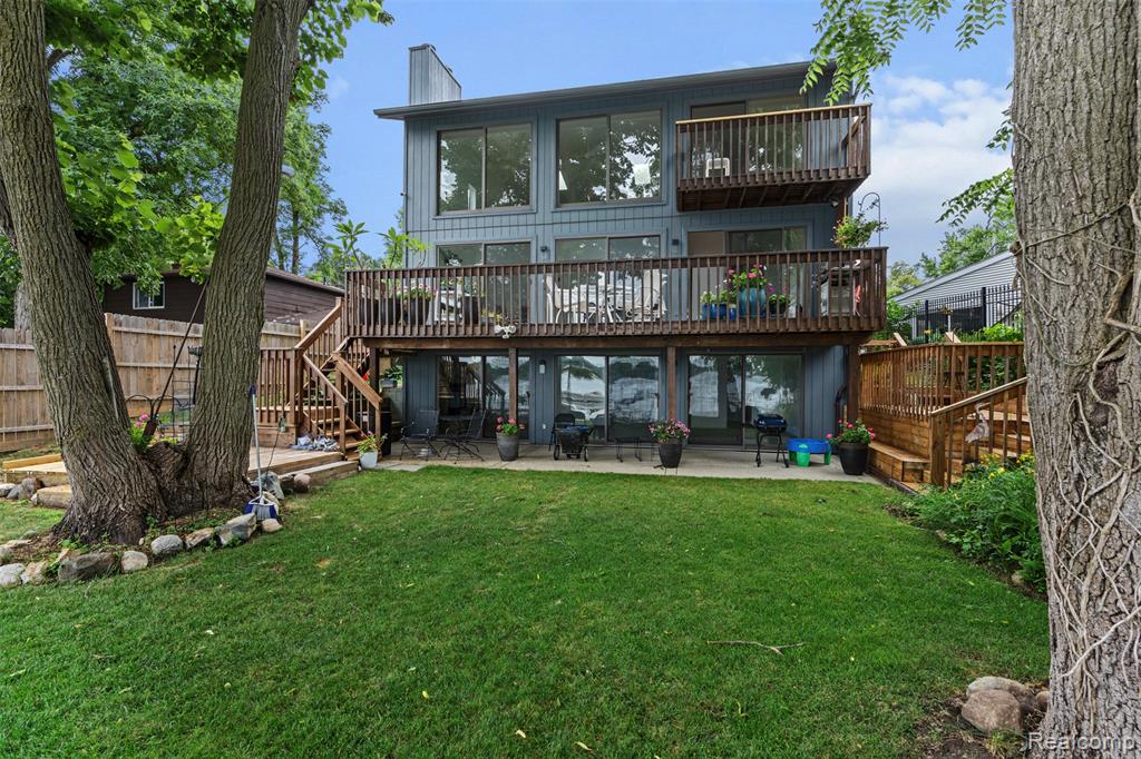 Experience the peace and tranquility of this updated contemporary lakefront home with 50 ft of frontage on the south shore of 367-acre private all-sports Elizabeth Lake and wonderful panoramic views from the 9 sets of lakeside Andersen door-walls! With over 3,400 sq ft of beautifully finished living space across three levels, this thoughtfully designed home blends elevated style and relaxed lake living. Built and lovingly maintained by its original owner, every inch reflects pride of ownership. The open-concept main floor features 18.5-ft vaulted ceilings, new white ceiling fans, oak hardwood floors, fresh white walls, and a great room anchored by a beautiful gas fireplace. The kitchen and all three full baths showcase granite countertops, porcelain tile, and lovely high-end fixtures. The top floor of the house is a serene primary suite with gorgeous lake views, a spa-like bathroom, walk-in closet, workout area, and access to both a private balcony and a large unfinished attic which is ideal for storage or additional living space. The large bright lower level walk-out features high-end carpeting (2023), full bath, second laundry room, second fireplace currently wood-burning but plumbed for gas for easy conversion, and 3 sets of door-walls to access the peaceful lakefront yard where you can relax in the shade of mature trees or bask in the sunshine! Additional updates include new driveway (2024), Canadian armor stone seawall ((2023), Lennox furnace and A/C (2023/2024), updated Guardian Alarm system (2025), wrought iron fencing, and 60-yr roof shingles (approx. 10-15 yrs old). Dock and 2015 Cypress Cay pontoon boat are available for purchase separately. Whether enjoying long summer days on the water or sipping cocoa by the fire while watching snow fall over the lake, this home is delightful year-round!