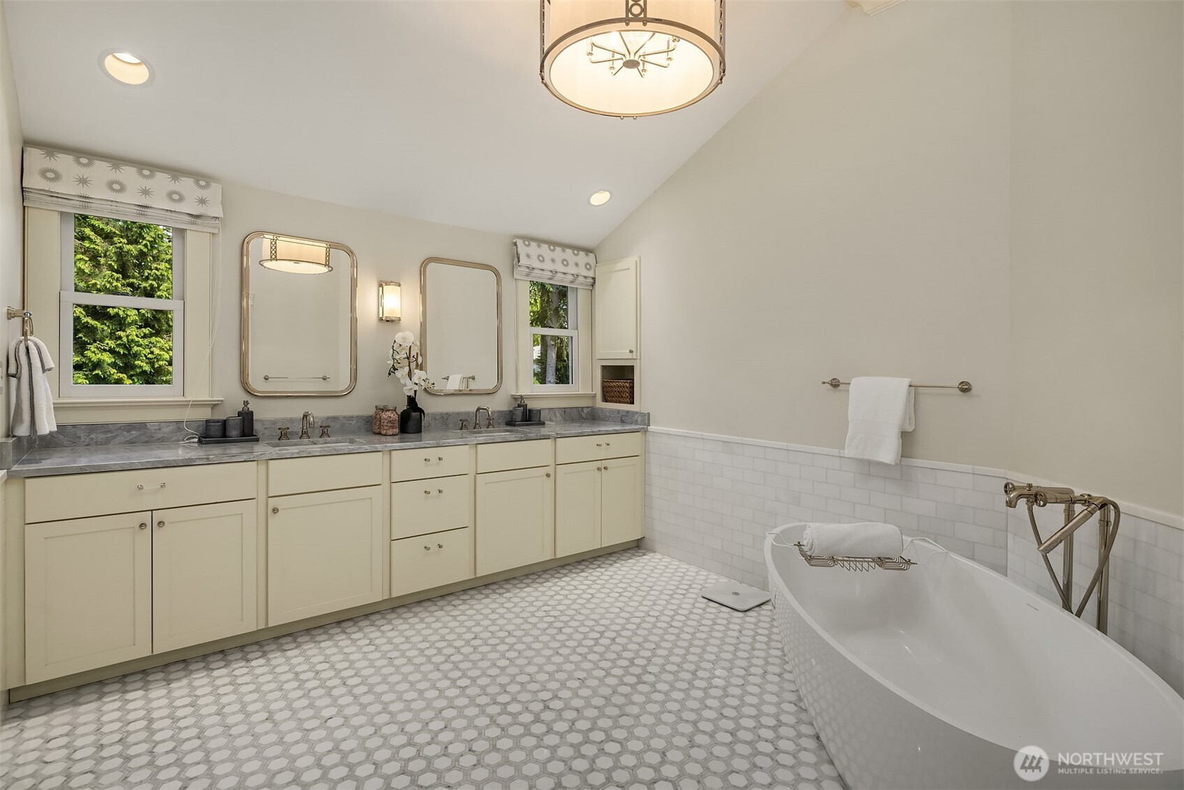 Primary bath boasts a soaking tub and dual vanity beneath vaulted ceilings