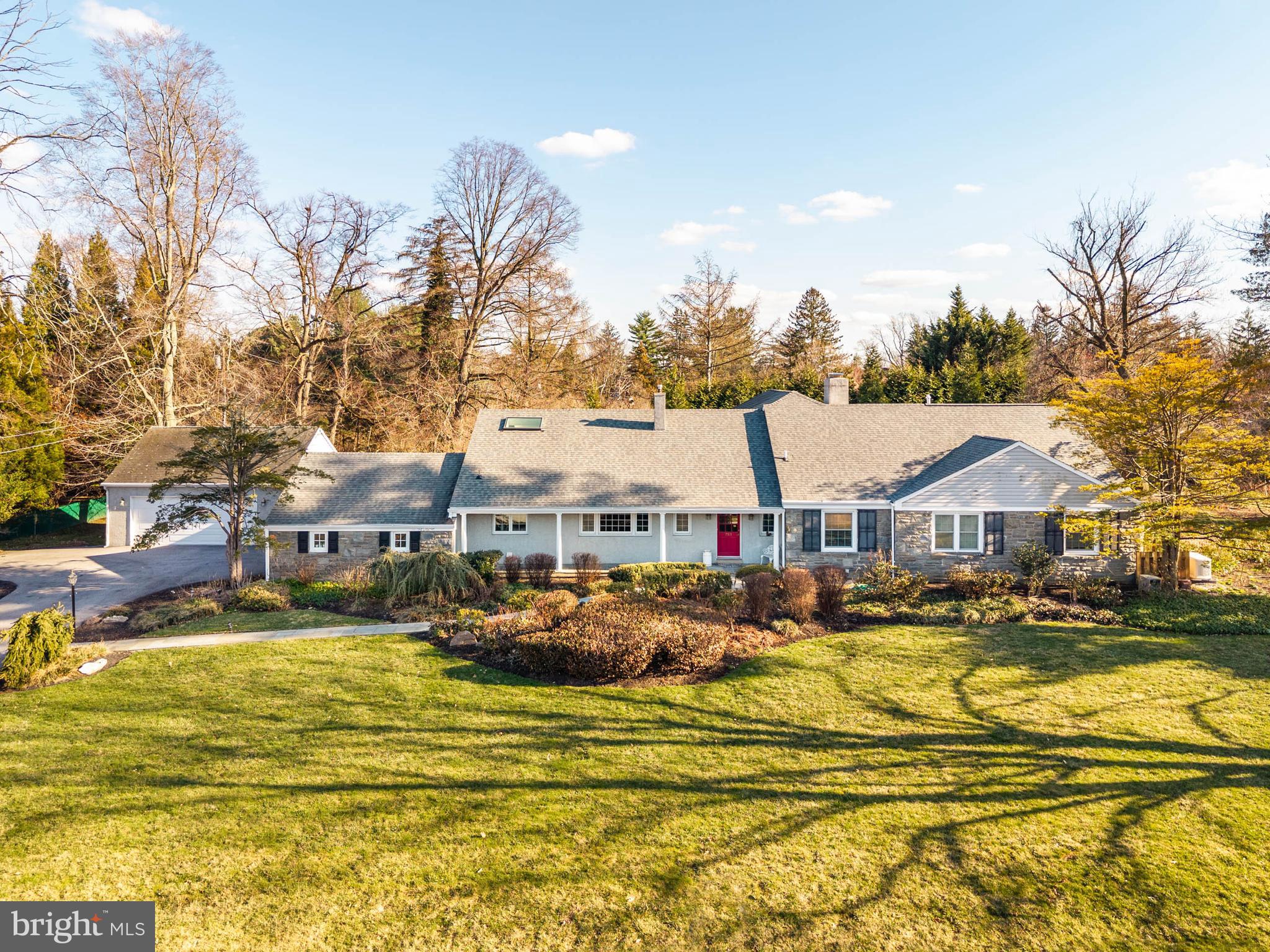 Set on a .71-acre level lot along one of Villanova’s most desirable neighborhood streets, this 5-bedroom, 3.5-bath ranch/Cape is surrounded by landscaped, highly usable grounds.A covered front porch introduces the foyer and a large living room anchored by a fireplace framed with built-in cabinetry. Just beyond, a sunroom overlooks the rear grounds and gardens.The dining room provides an inviting setting for gatherings and includes a large walk-in closet for serving pieces and entertaining supplies. Sliding glass doors extend the space to the patio, creating an easy connection for outdoor dining and entertaining.The kitchen has vaulted ceilings, a large center island, cherry cabinetry, quartz countertops, and a breakfast area with sliding doors opening to the patio. A family room with gas fireplace connects seamlessly to the kitchen, creating a comfortable everyday gathering space.The main level includes the primary suite with two walk-in closets and a bath with soaking tub and walk-in shower. A second bedroom on this level offers flexibility as a guest room or office. Additional main-level spaces include a laundry room, mudroom with vestibule to the two-car garage, and a separate office with built-in cabinetry and access to a third garage bay.The second floor offers three additional bedrooms, including one with its own bath, along with a hall bath and a large recreation room. A large unfinished basement provides extensive storage.Set among established homes in a sought-after Villanova neighborhood, the property combines a highly usable level lot, comfortable living spaces, and convenient access to the Main Line’s schools, shopping, and commuter routes.