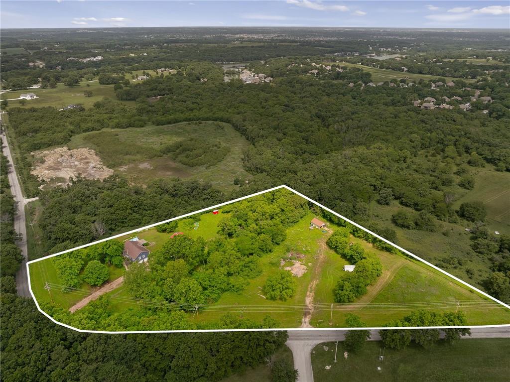 Rare opportunity to own 5+ acres with a Loch Lloyd address and no HOA!  Close-in acreage of this size is becoming nearly impossible to find. Mature trees, rolling terrain, and a beautiful creek running through the center of the property create a private setting just minutes from city conveniences.  The property includes a 3-bedroom, 2-bath ranch home, fenced pasture, and a 50' x 30' climate controlled outbuilding with concrete floor and electricity. With two existing access points from 171st Street and a previous homesite already established, there may be potential to divide the property into two tracts, subject to approval.  Whether you're looking to build your dream estate, create a family compound, or simply enjoy a rare piece of land in an exceptional location, this property offers endless possibilities in one of the most sought-after areas of the metro.