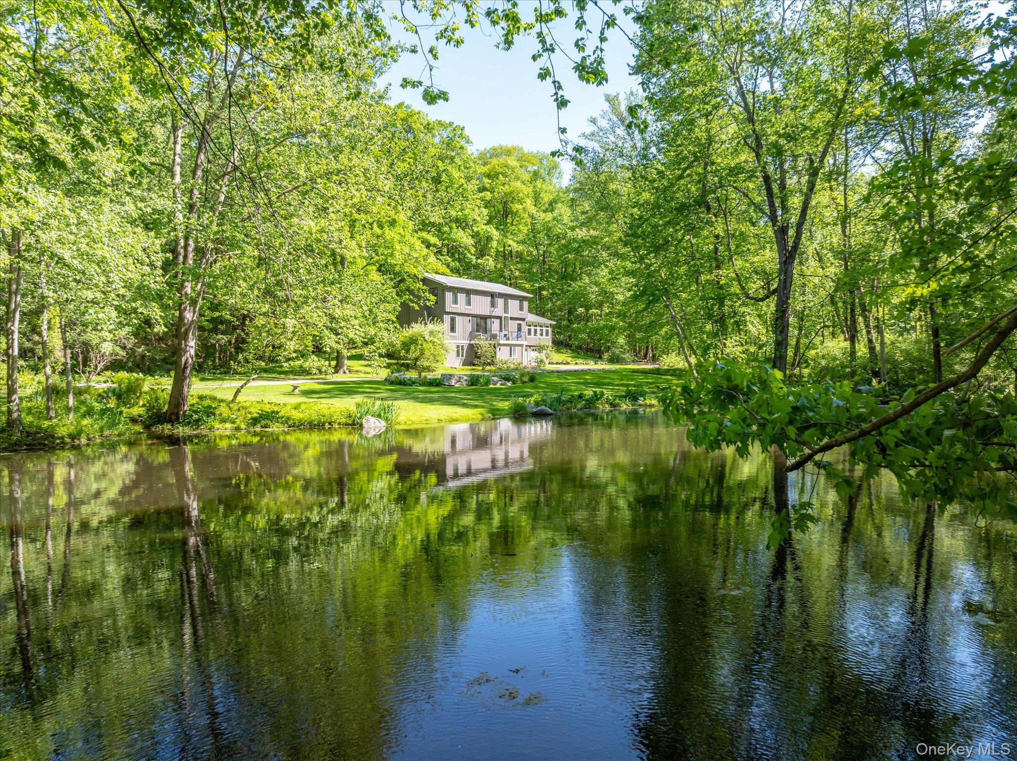 Welcome to 143 East Middle Patent Road in Bedford, New York—an extraordinary private retreat where contemporary living meets preserved natural landscape. While photographs offer a glimpse, the experience of the property—its scale, privacy, and stillness—can only be fully understood in person.Set on 4.19 secluded acres, the residence overlooks a serene sylvan pond, revived with an active spring feed. The water invites quiet moments by the pond’s edge, picnics in nature, or canoeing across its calm surface. The property is fully surrounded by mature woods and directly borders a 72-acre nature preserve, offering uninterrupted views of rocky hillside and untouched forest. A long, private driveway reinforces the sense of arrival and complete privacy.The home is equally compelling across seasons—whether enclosed in winter snowfall or opened fully in summer to indoor-outdoor living. Storms, stillness, and shifting seasonal light all become part of the daily backdrop.Built in 1986, this 3-bedroom, 3-bathroom contemporary offers an open floor plan designed for entertaining and comfortable everyday living. It serves equally well as a full-time residence or weekend retreat for New York City buyers seeking privacy, nature, and convenience in Westchester County, just minutes from Bedford Center in Bedford, New York and its restaurants and amenities, with nearby rail access at Mount Kisco, New York providing a direct connection to Manhattan.Interior spaces include a walk-out lower level, two-car garage, and extensive on-site parking. The lower level adds approximately 600 square feet of finished space, including a gym and laundry area, bringing total living area to approximately 3,529 square feet.A comprehensive renovation elevates the home throughout, including all new water filtration systems, windows, doors, floors, insulation, and a fully redesigned fireplace featuring blackened steel and a solid brass gas hood. The kitchen is finished in solid walnut, and all bathrooms have been fully renovated. The primary suite includes heated bathroom floors and a custom California Closets walk-in system valued at approximately $25,000.Outdoor improvements include a newly constructed deck overlooking the grounds and a revived pond supported by an active spring feed that enhances both its natural beauty and ecological character. The home is also equipped with 3-zone heating for year-round comfort.Tax details are as follows: Town and County (2026) $6,238.95, School Taxes (2025–2026) $13,535.08, Total Gross Taxes $19,774.03, STAR exemption reduces taxes by $1,062 bringing the total to $18,712.03, and Senior STAR reduction $2,457.Bedford Village continues to evolve with renewed energy, including destinations such as Mast Market and OHHO at the old firehouse, while maintaining its historic charm and character.This is a property defined not only by its improvements and setting, but by its rare sense of privacy, presence, and permanence.Enjoy a glass of cold lemonade on the deck, where time slows and the landscape speaks for itself. Sunrises and Sunsets included.
