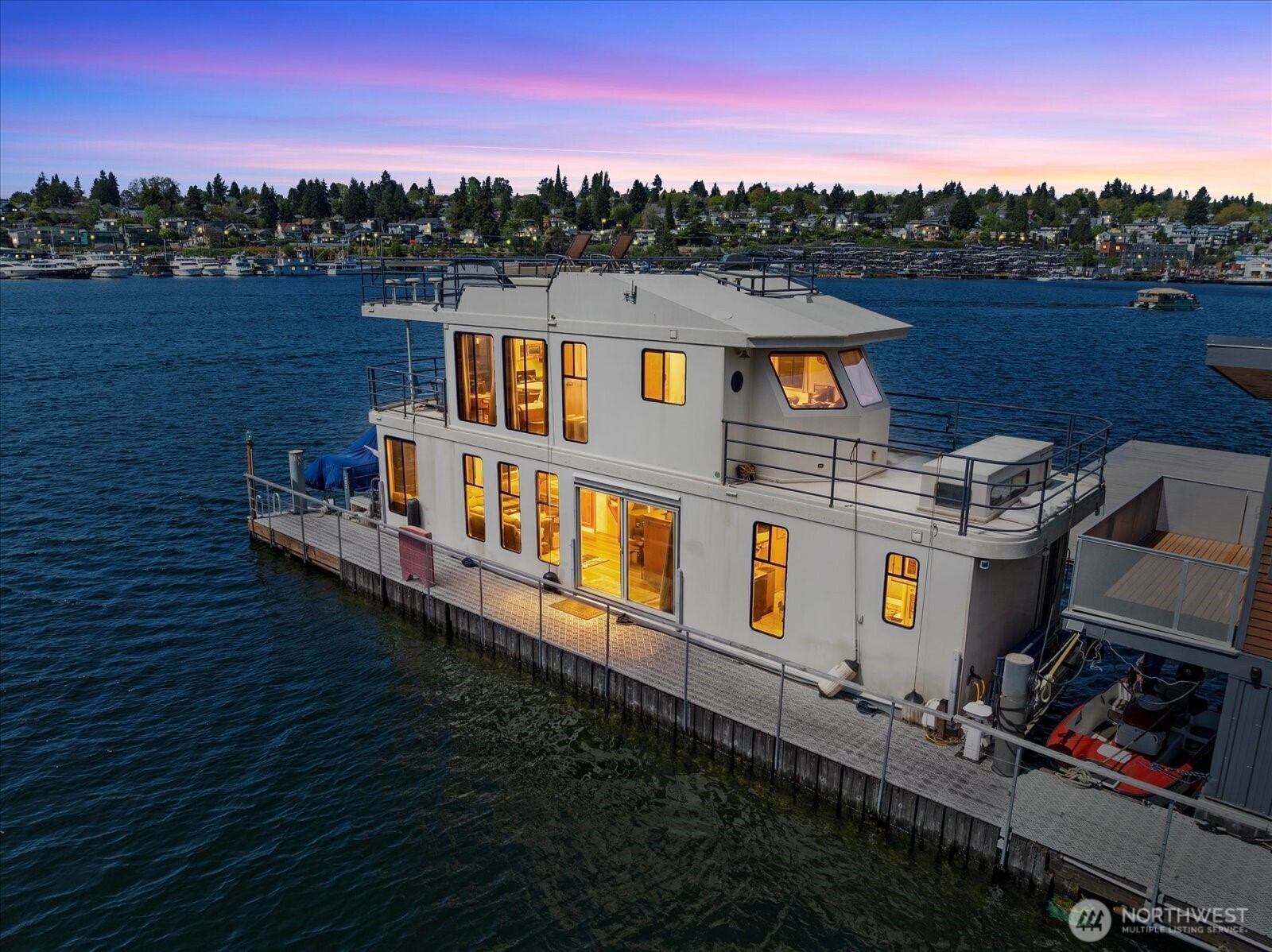 End-of-dock opportunity—fee-simple OWNED 50’ x 15’ slip, rare on Lake Union. Expansive indoor/outdoor living with unobstructed open-water, skyline, and Space Needle views from nearly every level. Front row seat for Fourth of July and New Year's fireworks, Seaplane taking off and landing.    Main level features an open kitchen with oversized countertop, dining, and a spacious living area with a fireplace. The primary suite offers direct lake access through dual patio doors. Upstairs, a large bonus room with a built-in office and covered view deck leads to a rooftop retreat with a hot tub, bar seating, and panoramic views. The lower level provides additional sleeping space for guests.    Electric davit and dinghy with motor included. Option to become a member of the college Club with an additional fee.    30+ day rentals permitted with HOA approval, offering flexibility for extended stays or income potential. Financing available. Low HOD's at $492/mo include water, garbage, and electricity. HOA is working on adding a sewer line for the dock (no special assessments).    Connected to the Cheshiahud Lake Union Loop and minutes to the Burke-Gilman Trail—bike to Downtown, UW, and tech campuses. Walk to your favorite dining, enjoy Husky games, bike to downtown, or take transit and access the light rail nearby.    Rare combination of owned moorage, end-of-dock position, and experience the amazing Lake Union Living lifestyle.