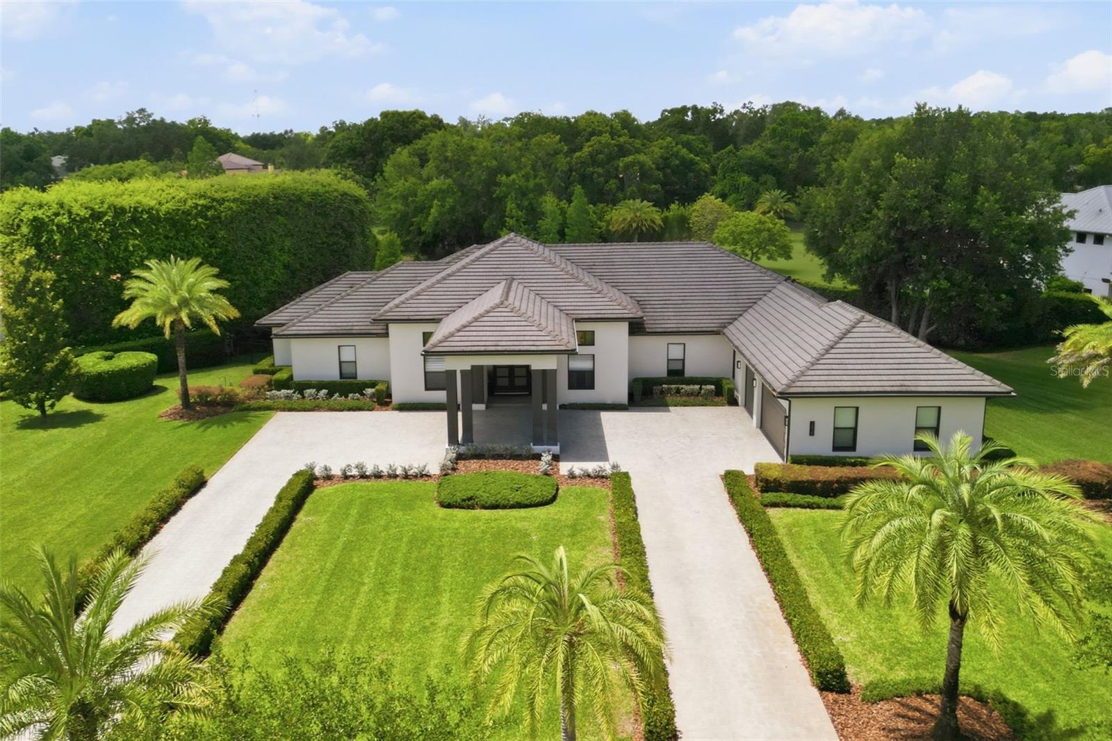 Under contract-accepting backup offers. Welcome to the modern estate you’ve been waiting for, located on just over an acre in The Sanctuary on Livingston, one of Lutz’s premier gated communities just minutes from Tampa. Positioned on a private corner homesite with conservation and pond views, this 2018-built residence offers over 4,400 square feet with 4 bedrooms, an office/flex space, and 4.5 bathrooms designed for both everyday living and entertaining.Inside features soaring ceilings, coffered details, panoramic windows, and designer finishes create a bright, open atmosphere throughout. The split floor plan provides privacy, with the primary suite occupying its own wing featuring a spa-inspired bathroom with floating vanities, soaking tub, oversized walk-in shower, and a large custom walk-in closet. Additional bedrooms are thoughtfully positioned on separate wings and include spacious layouts, custom closet systems, and updated finishes.The chef’s kitchen is equipped with premium Viking appliances, including a gas 6-burner range and oversized refrigerator, along with quartz countertops and backsplash, custom cabinetry, a 72-inch center island, and a large walk-in pantry with built-in organization.The great room showcases panoramic backyard views, 15-17 foot coffered ceilings through the home, and a custom tile-and-stone entertainment wall with a 60-inch electric fireplace and built-in storage. Completed in 2025, the resort-style pool and spa transformed the outdoor living space into a private retreat featuring swim-up bar seating, a sunken fire pit lounge, travertine decking, updated landscaping, irrigation, landscape lighting, and over 50 feet of covered outdoor living space. The expansive rear porch includes over 50 FT. of covered area for entertaining and dining! Equipped with an outdoor kitchen and bar, dining area, fireplace, and safety fencing overlooking peaceful water and conservation views.Additional upgrades include full panic "safe" room off of master closet equipped with metal sheathing on all sides, and double plywood with 3/4 inch drywall fixed directly to the slab for weather and crisis protection! The Great Room and Primary Suite have automated blinds and custom blinds in other areas, UV window treatments, buried propane tank, U-shaped paver driveway, oversized breezeway entry, 3-car garage with EV charging prewires, concrete tile roof, smart home and security integration, extensive storage systems, and well and septic systems resulting in no water or sewer bills.Residents of The Sanctuary on Livingston enjoy gated privacy, sidewalks, playgrounds, and park amenities with convenient access to I-275, I-75, the Veterans Expressway, and Dale Mabry Highway. Downtown Tampa, shopping, dining, golf courses, hospitals, and Tampa International Airport are all nearby while still offering the peace and privacy of estate-style living.Homes offering this level of outdoor living, lot size, privacy, and modern finishes rarely become available in The Sanctuary on Livingston.