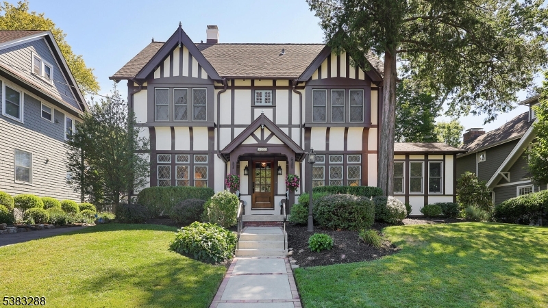 Captivating Tudor with 5 bedrooms, 2.2 bathrooms and a 1 car garage offers timeless curb appeal in a desirable Westfield neighborhood, close to schools, a vibrant downtown, and train to NYC. This home blends classic craftsmanship with a bright, open feel. Highlights include leaded stained glass windows, elegant trim work, beautiful hardwood floors, and period touches which enhance its character. A charming covered-porch entry welcomes you inside to the living room with a wood-burning fire place. The dining room is warm and welcoming, and flows into a beautifully appointed kitchen with exposed brick beam framing the center island, crisp white cabinetry, a farmhouse sink, pot filler, stainless appliances, a double gas oven, and a gas cooktop. The kitchen overlooks the private yard perfect for relaxing or entertaining. A hallway with a powder room leads to the inviting family room, complete with French doors to the back patio and a wet bar. Convenient first floor stacked laundry, a full bath with a stall shower, and a versatile bedroom or office complete this floor. Upstairs are three bright bedrooms, one with a private half bath. The spacious primary features a stunning walk-in closet, and a stylish hall bath completes the level. The third floor offers an additional bedroom, laundry area, and generous attic storage. With an unfinished basement for future use, this home pairs historic charm with everyday comfort - all just moments from vibrant downtown Westfield.