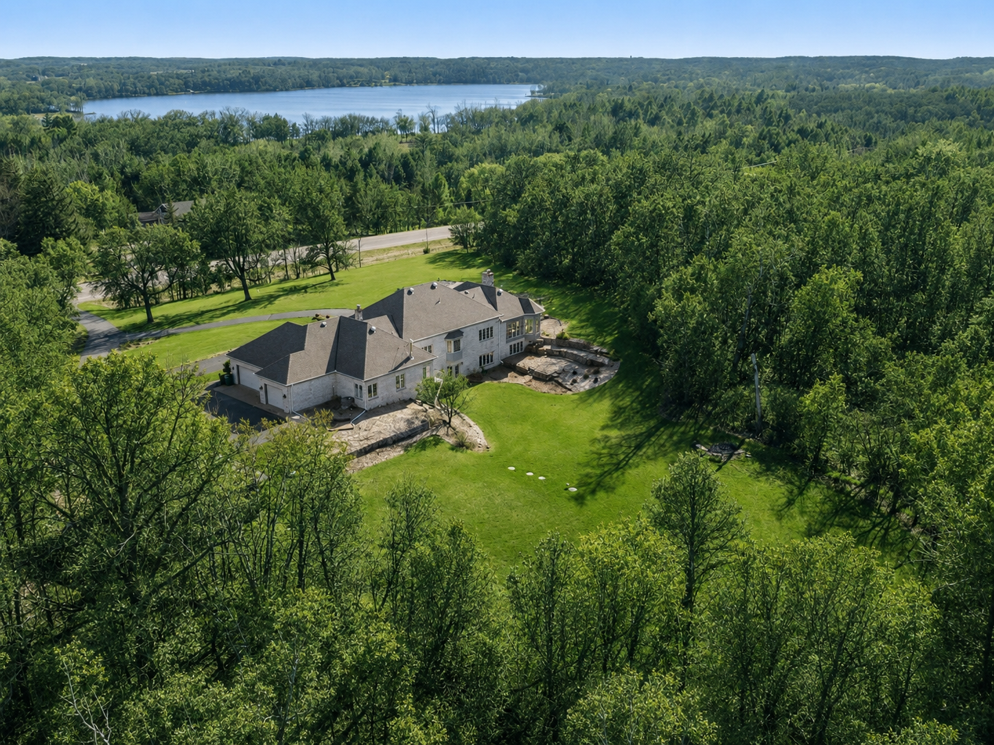 This stately Saint Joseph retreat sits on twenty acres of rolling hills and offers more than 6,500 finished square feet, with a thoughtfully designed floor plan that seamlessly blends elegance with expansive indoor and outdoor living. Ideally located just minutes from I-94, the property is within walking distance of live music and events at Milk & Honey and only minutes from downtown Saint Joseph. Nearby college campuses, including the College of Saint Benedict, Saint John’s University, and St. Cloud State, add vibrancy and culture to the area.Arrive via the circular driveway and take in the home’s sophisticated curb appeal, featuring a grand front entry, timeless brick finishes, and impressive wings extending from both sides of the residence. Outdoors, the property is a private sanctuary with scenic walking trails, perennial gardens, wild apple trees, blackberries, and abundant wildlife.Inside, the home offers four bedrooms and four bathrooms, along with expansive spaces ideal for entertaining. Multiple living areas and sitting rooms provide both comfort and versatility. The chef’s kitchen features a gas range, large center island, abundant natural light, generous storage, a wet coffee bar, and a spacious dining area accented by French doors leading to a brick patio. Guests are welcomed through a large foyer into an elegant parlor that offers additional dining or gathering space, highlighted by a genuine Austrian crystal chandelier.Just off the kitchen, the great room showcases vaulted ceilings, custom built-ins, and a gas-burning fireplace. The tiled sunroom includes a wet bar, patio access, and expansive windows that frame the surrounding natural landscape. The lower-level living space centers around a sunken seating area with striking custom stonework, a wood-burning fireplace, and a convenient kitchenette, perfect for entertaining or relaxing.For a truly private retreat, the sprawling primary suite features its own sitting area, private balcony, and gas fireplace. The en-suite bathroom offers heated floors, a large soaking tub, a separate multi-head shower, a double vanity, and a walk-in closet.The property includes exceptional storage throughout, with a total of five garage stalls: an attached, heated, and insulated three-stall garage and a detached two-stall garage with additional storage space. A large utility room with floor-to-ceiling shelving, along with an adjoining storage room, adds even more functionality. The roof and gutters are less than three years old.This remarkable home must be experienced in person to fully appreciate its unique character, thoughtful design, and exceptional setting.Don’t miss this rare combination of acreage, privacy, and prime location.