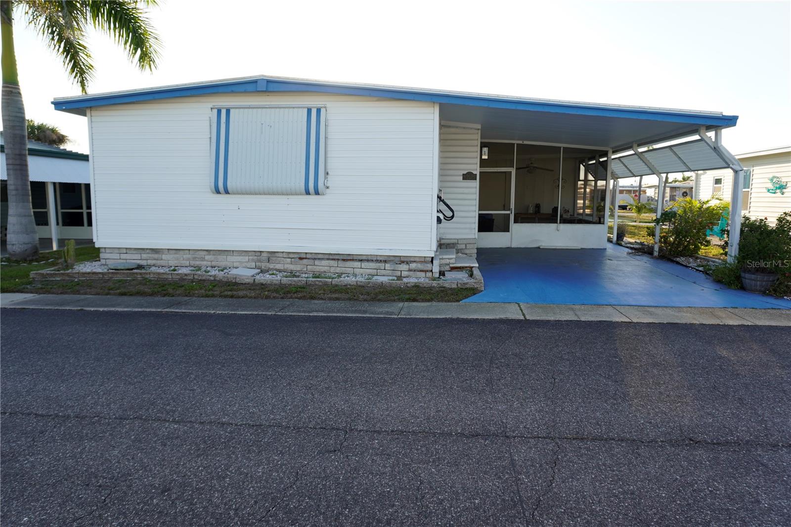 Discover this 1970s 2 bedroom, 1 bathroom double-wide manufactured home located in a vibrant 55+ community. This home offers and update roof and A/C system that are only 3 years old. The floor plan features a generous sunroom addition that significantly boosts the square footage, providing the perfect bright space for a hobby room or lounge. Additionally it also offers a covered car port with an outside patio and workshop storage room. While it needs some minor cosmetic touching up, it presents a fantastic opportunity to customize your dream retreat. Enjoy fantastic community amenities and a prime location just minutes from major roadways, shopping, and dining.