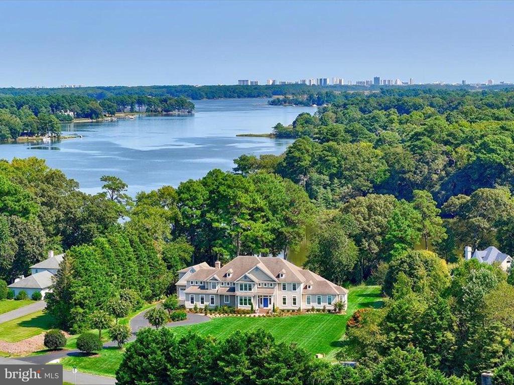 This stunning waterfront estate home in the Cedar Creek community blends Coastal and Transitional architecture. Surrounded with ultimate luxury, comfort and breathtaking accents, this thoughtfully designed and well-appointed custom-built home by White Creek Homes, LLC. is sited on 2+ waterfront acres and a natural shoreline. Standing at the ready, a private dock, an upgraded boardwalk invites water activities including jet skiing, kayaking, canoeing, fishing or just relaxing in the sun. Enjoy endless entertainment venues including a screened porch, Professional landscaping and hardscaping including expansive paver patios, as well as a gas hook up for grilling and fire pit. Inside, a gracious foyer is sided by formal living with a fireplace and built-ins, and a formal dining room opposite with a bay window, designer chandelier and adjacent wet bar with wine cooler.  The extended foyer draws your sightline and offers immediate access to outdoor living and water views. Tailored to perfection, the main level living offers elevator service to all three levels and a private wing with a secluded primary bedroom suite with water views, a dressing room, two walk-in closets and a spa like luxury shower and jetted tub.Windows abound and frame water views in a stunning work at home office outfitted with refined coastal paneling and a wall of built-in cabinetry. Robust with light streaming from waterside windows, the adjacent breakfast room embraces water views on one side and an outstanding chef's kitchen on the other side.   A commanding entertainers island with a breakfast bar and pendants is accompanied by Wolf Appliances, custom cabinetry, back splash and full size Sub-Zero fridge and freezer seamlessly paneled and flanking a barrel vaulted Dutch door that opens to a secondary side entry, drop cubbies, half bath, and second laundry.  The thoughtfully curated floor plan unfolds seamlessly to a family room crowned by a dramatic vaulted ceiling and decorative trusses adding a curated and artful aesthetic with access to the screened in porch.  Entertaining venues allow guests to meander from outdoor to indoor spaces by way of the screened porch, central hall  porch, or side secondary entry.  Enhancements that conclude the main level include an extended butler’s service station, dry-bar with kick-vac and secondary back stair.  Upstairs, there are four more en-suite bedrooms, a guest flex bedroom, and a spacious laundry room with cabinetry, surfaces for folding, and a utility sink.  Another winding staircase with a sun-lit landing rises to the billiards area, half bath, and recreation room with more inviting panoramic views from the waterside balcony on the top level. This resort styled property is serenely private and secluded, yet within minutes to the vibrant amenities in nearby Ocean City by car or pontoon.   Design elegance, quality finishes, and attention to detail distinguish this home from all others, and it will surely satisfy every expectation with every imaginable amenity. Come home to a very special lifestyle with enduring waterfront comfort and quality that has been immaculately maintained.
