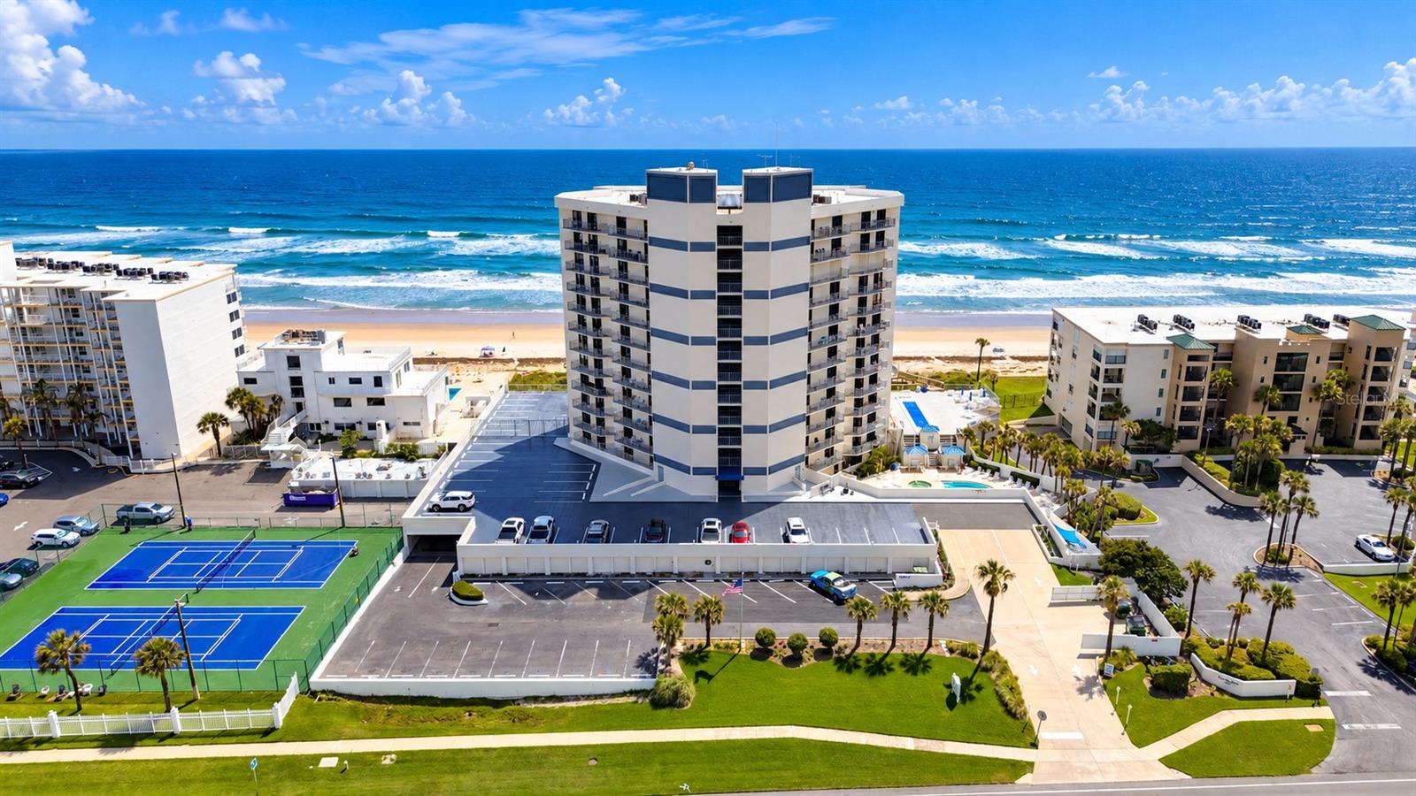 Experience breathtaking panoramic views from this beautifully updated, 2-bedroom, 2-bath oceanfront condominium at Seascape Towers, ideally situated along the peaceful, no-drive beach in New Smyrna Beach. Perched high above the coastline, this desirable south-facing residence features THREE separate balconies offering spectacular 180-degree views stretching from the Atlantic Ocean to the Intracoastal Waterway. Enjoy stunning sunrises over the ocean, colorful sunsets toward the river, and sweeping coastal scenery from multiple vantage points. Inside, the light and bright, open floor plan features upgraded wood-plank tile flooring throughout, fresh interior paint, and a spacious living room designed for comfortable coastal living. The kitchen boasts granite countertops and upgraded appliances, while the generously sized living area includes a sleeper sofa to accommodate additional guests. The primary suite offers a walk-in closet and private en-suite bathroom featuring a large walk-in shower with multiple shower heads. Additional conveniences include full-size, in-unit laundry with separate washer and dryer, a NEW HVAC system (2025), and a NEW water heater. Best of all, the furniture is included, making this residence ready for immediate enjoyment! Whether you're searching for a beachfront getaway, full-time residence, or income-producing investment, this property offers exceptional versatility, with weekly rentals permitted most of the year and two-week minimums during the winter months. Seascape Towers offers an impressive collection of resort-style amenities, including a heated oceanfront swimming pool thoughtfully positioned to maximize sunshine and provide protection from cooler seasonal winds, a hot tub, spa, secure building access, parking garage with bicycle storage, and a private storage locker. HOA fees conveniently include high-speed internet, cable TV, water, sewer, trash, and maintenance of the grounds and amenities. The community is also pet-friendly for owners. Located directly on New Smyrna Beach's sought-after no-drive beach, residents enjoy a quieter, more relaxed coastal atmosphere without vehicle traffic on the sand. This prime location is just 3 miles from Canaveral National Seashore, 5 miles from the restaurants, shops, and entertainment of Flagler Avenue, and 2.4 miles from the waterfront dining at JB's Fish Camp.