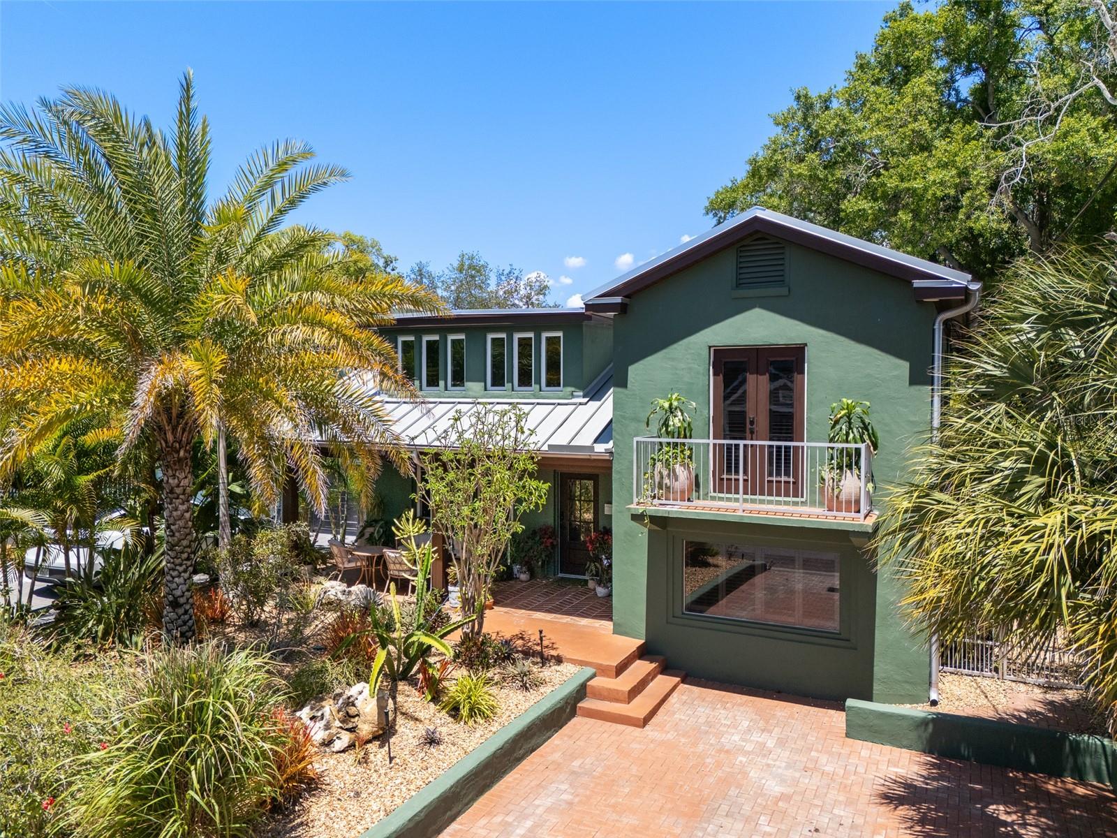Welcome to this beautifully appointed residence full of charm and warmth, in the sought-after Plant High School district and not in a flood zone. Outstanding curb appeal welcomes you immediately with a classic brick driveway leading to a peaceful covered front porch featuring a remarkable wood ceiling and natural landscaped front yard. Enter inside to discover a thoughtful interior elevated by large profile ceramic tile floors, gorgeous wood-framed windows outfitted with custom plantation shutters, craftsman baseboards and doors, smooth drywall and a curved staircase. The inviting living room, centered around a stylish brick fireplace, flows seamlessly into a bright and abundant redesigned kitchen. This culinary space is ideally equipped with an induction cooktop, built-in oven and microwave, a sleek farmhouse sink, and an oversized island that cleverly incorporates a dedicated table seating area for casual dining and entertaining. The home continues to impress with a luxurious primary bedroom that boasts its private front-facing balcony for morning coffee or evening relaxation. The secondary bedrooms offer fantastic versatility, in flexible spaces that could be an office, study or craft room, in addition to large bonus room on the first level. The guest bedroom has a wood deck overlooking the scenic backyard. The upstairs bath features a chic tile wall, timeless clawfoot bathtub and two sinks, while the downstairs has an elegant half bath and the second full bath. Key updates include a metal roof, and replaced windows, with remodeled kitchen and bath aspects in 2022. The private backyard oasis, highlighting an aesthetic wood fence, tall landscaping, complemented with low-maintenance turf backyard designed for year-round enjoyment, comes complete with a covered seating area ideal for outdoor gatherings. Conveniently in the Palma Ceia area of South Tampa, just blocks from Bayshore Boulevard, and close to Hyde Park Village, downtown Tampa and Tampa International Airport.