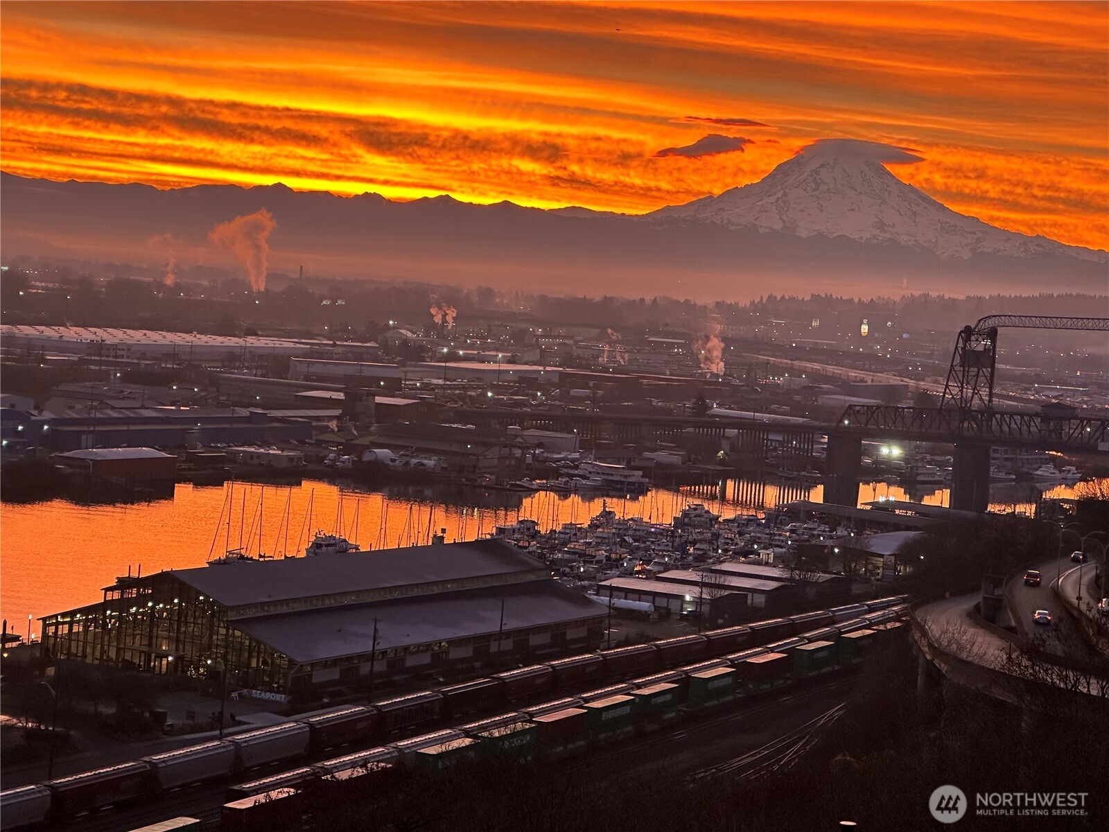 Wonderful views of Puget Sound’s Commencement Bay, Port of Tacoma, Mt. Rainier, Tacoma city and waterways from this luxury condo perched high above Dock St. shoreline. Enjoy first-class sunrises and views all day every day. Generous living area includes large built-in bookcase and gas fireplace and balcony. The Primary suite features a large finished walk-in closet, while the second BR features a built-in Queen-sized Murphy bed. The kitchen has stainless appliances with a built-in drink fridge, rounding out the spacious 1600+ square foot floor plan. Painted wooden crown molding adorns the nine-foot ceilings throughout.  Other luxury amenities include hotel class HVAC, dedicated car wash station and hobby room. But that’s not all—the stunning 9th floor SkyLounge common area offers more great views but also a full kitchen and party room for owners and their guests, a gym and even a guest suite for visitors and family who wish to stay over. Comes with two adjacent secure underground parking spaces. Walk two blocks to McMenamin’s Elks Temple restaurant, Corina’s Bakery, the Grand Theater for a movie or the Pantages Theater for a concert or show. Conveniently located on SoundTransit “T” line for access to almost anywhere.