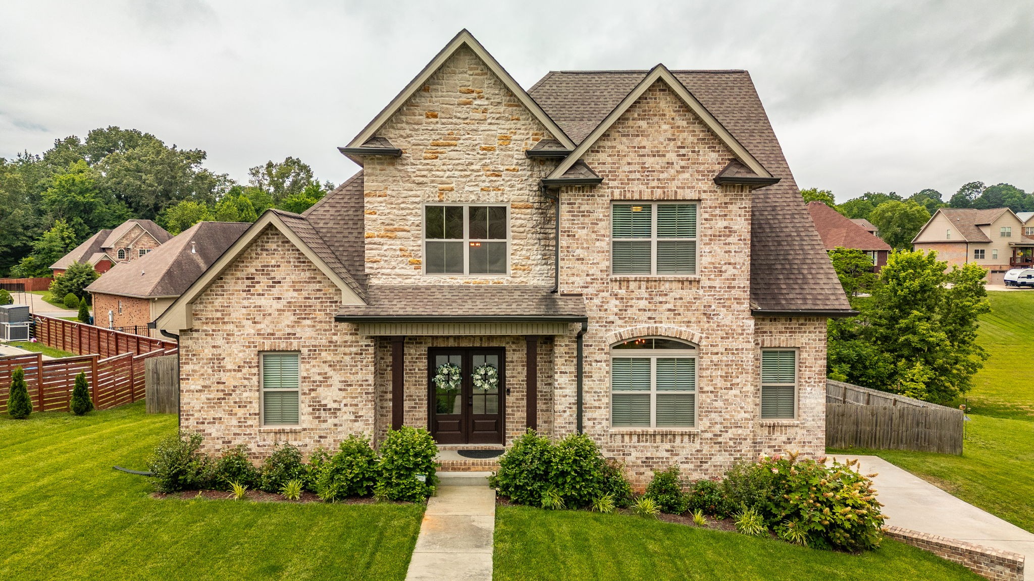 From the moment you step onto the charming covered front porch and through the double doors, this home will leave you breathless. Inside, a shiplap-accented foyer and gleaming hardwood floors set the tone for style and warmth. The gourmet kitchen is a dream with white cabinetry featuring glass fronts, granite counters, a tile backsplash, rustic wood ceiling beams, and a huge island with a farmhouse sink — all open to a cozy great room with a stunning stone gas fireplace and raised hearth. The primary retreat is your sanctuary with a soaking tub, walk-in shower, double vanities, and an oversized closet. Upstairs boasts spacious secondary bedrooms and a full bath, while the finished basement offers a large rec room and additional full bath — ideal for guests or game nights! With a massive 3-car garage, covered deck, and fenced backyard, this home truly has it all. Don’t miss your chance to fall in love!