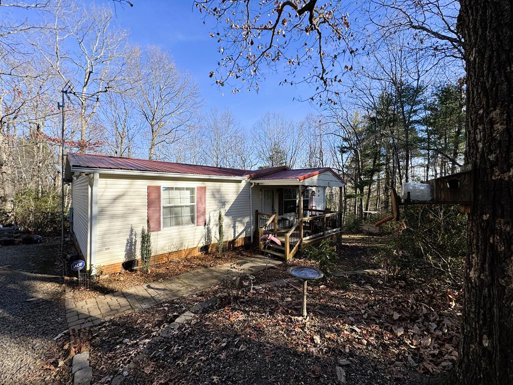 This manufactured home offers 1,080 sq ft of heated living space on the main level. It sits in a private, secluded setting within Trout Run Estates. The floor plan includes a living room, kitchen and dining area, laundry room, bedroom, bath, primary bedroom, and primary bath with a newly installed walk-in shower. A front porch and back deck provide comfortable outdoor areas to enjoy the surroundings. The home is equipped with a whole-house generator, heat pump, and tankless water heater.  The property features a detached 2-car garage with a lean-to, insulated ceiling, and concrete floor. A garden area is available for planting, and two of the three storage buildings will convey. The 5 acres of land are rolling, and the circular driveway offers convenient access.  This property is located in a Gated Community with access to the Smith River by the Community common area which is located on the Smith River.