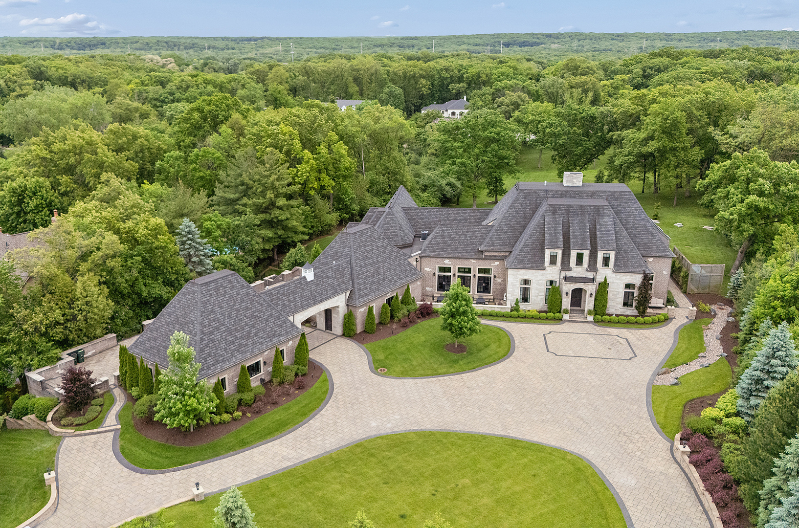Welcome to one of Burr Ridge's most extraordinary luxury estates, privately situated on 3.2 acres with the opportunity to purchase the additional rear parcel and expand the property to nearly 4 acres. Vacant lot at rear of property is 3/4 of an acre. Owner is asking $400,000. The lot adds quite a bit to the depth of property.  Designed and built with exceptional craftsmanship, this custom residence combines grand-scale living, resort-style amenities, and unmatched privacy in one of the most sought-after locations in the western suburbs. Constructed with extensive steel beam construction and flexicore flooring systems, this home offers quality and durability rarely found today. From the moment you enter, soaring 12-foot ceilings on the main level and 11-foot ceilings in the walkout basement create a sense of elegance and openness. Nearly every room showcases breathtaking views of the surrounding grounds, pool, and natural landscape where deer are often seen passing through. The heart of the home is the spectacular open-concept living area. The chef's kitchen features a Wolf range, double ovens, Sub-Zero refrigerator, oversized granite island with two built-in food warmers, abundant cabinetry, extensive counter space, and a walk-in pantry. The kitchen flows seamlessly into the eating area, family room, entertainment bar, and stunning hearth room with fireplace and panoramic backyard views. Designed for entertaining, the outdoor living spaces are second to none. A breathtaking infinity-edge pool with waterfall and fire bowls is surrounded by multi-level custom Italian stone patios, expansive gathering areas, and outdoor fireplaces, including one already roughed in. The large veranda provides the perfect setting for morning coffee or evening relaxation. All outdoor patio and pool furniture will remain with the home. The main level also features a private guest suite with full bath and separate entrance, ideal for related living or long-term guests, a formal dining room with patio access, and a private office or living room. The luxurious first-floor primary suite offers stunning yard views, private balcony access, a remarkable 21x14 walk-in closet with granite wardrobe island, and a spa-inspired bath featuring dual vanities, custom shower, soaking tub, and premium finishes. A mudroom leads to the heated 6-car garage with epoxy floors. One of the three-car garages is air-conditioned, while another bay includes a vehicle lift, allowing storage for up to seven cars, making this property a dream for collectors and enthusiasts. Upstairs, you'll find three spacious bedrooms, two with private baths, plus a versatile 25x17 loft that can serve as a family room, media space, office, or lounge. A covered balcony overlooks the pool and estate grounds. The largest bedroom includes a large walk-in closet and nearby laundry access. The walkout lower level is an entertainer's dream. A second full kitchen with center island and walk-in pantry anchors the space, alongside a massive recreation area, theater room, workshop, mechanical room, and a large gathering and dining area ideal for hosting pool parties and special events. A full bath, laundry room, and additional garage bay for lawn equipment complete the lower level. Additional features include an elevator servicing all three levels, whole-house generator, extensive storage, dual laundry areas, and the possibility for much of the newer indoor and outdoor furniture valued at over $200,000 to remain with the home. Located just minutes from I-55, Burr Ridge Village Center, upscale dining, shopping, spas, and entertainment, this remarkable estate offers a rare opportunity to enjoy luxury, privacy, and resort-style living in one of Chicagoland's premier communities. This is truly a home that must be experienced in person to appreciate its quality, scale, and setting.  POF or Pre-approval needed before showing
