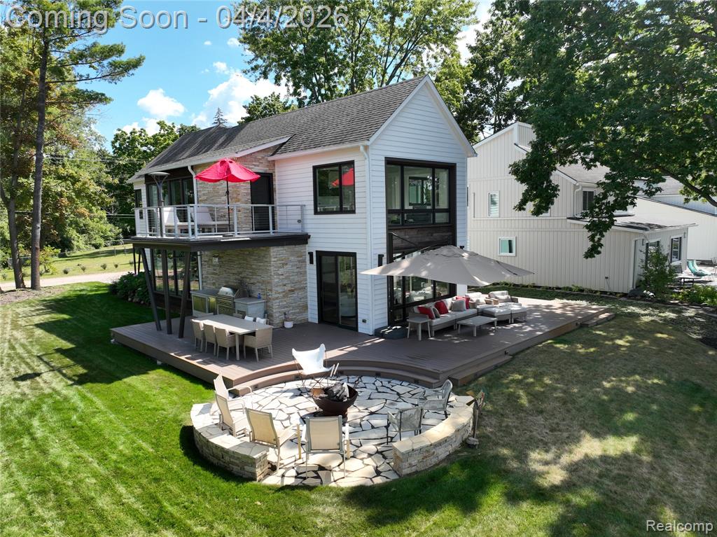 Discover a rare blend of architectural sophistication and effortless lakefront living on the shores of Zukey Lake. With 74 feet of lake frontage and access to the entire Huron River Chain of 9 Lakes, this 2021 custom residence. Designed by the acclaimed Angelini & Associates Architects of Ann Arbor, and showcased on the cover of Michigan Blue—offers a level of design and craftsmanship that stands in a class of its own. Inside, more than 3,200 sq ft of living space unfolds in an open, airy layout framed by soaring ceilings, quarter-sawn oak floors, and expansive walls of glass that draw the lake into every corner. The kitchen is a striking modern centerpiece with flush white cabinetry, cast concrete aggregate countertops, premium stainless appliances, bar refrigerators and a generous island. The great room is designed for both comfort and drama, featuring a stacked stone fireplace and multiple seating zones oriented toward water views. Oversized door walls open to an outdoor living space that rivals a private resort w/ an expansive composite deck complete with a full outdoor kitchen, built-in BBQ, refrigerator, circular firepit, and multiple seating areas. The lakeside primary suite offers a private retreat, with its own balcony for sunset watching, a beautiful walk in closet by California Closet with dressing area, and a spa-like bath with dual sinks and a tiled walk-in shower. Main-floor office adjacent to a full bath offers flexibility for a fourth bedroom.  Each level has a laundry room equiped with washer and dryer.  Additional features are: efficient split zone HVAC, on demand hot  water, sprinkler system, whole house generator and Hardy Board siding.  Just steps from the Lakeland Trail, perfect for biking and running.  This property isn’t simply a home—it’s a year-round escape, a modern design statement, and a rare opportunity to own one of Zukey Lake’s most exceptional waterfront residences.