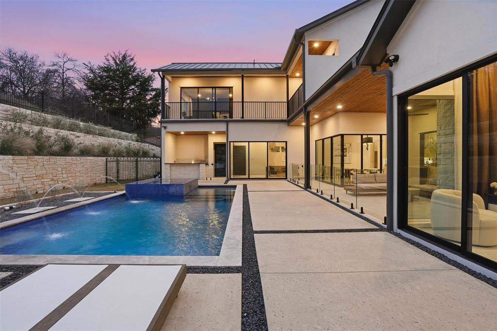 Nestled in one of the most distinctive, private neighborhoods in Fort Worth is this contemporary masterpiece, built by Heritage Homes- a Fort Worth Magazine Dream Home Builder. Step into architectural elegance situated on a premier lot overlooking abundant trees and trails. Inside, you're welcomed by soaring ceilings, sleek hardwood floors, and a dramatic open concept living space anchored by a statement fireplace. A wall of zero-post sliding glass doors effortlessly merges indoor-outdoor living and frames your private backyard resort. The show-stopping kitchen boasts a bold black-and-white waterfall island, custom cabinetry, designer lighting, and high-end appliances — seamlessly complemented by a full prep kitchen tucked away for effortless entertaining. A wraparound balcony off the upper level offers serene views, while the versatile bonus room adapts to your lifestyle as a media, gym, or guest suite. Retreat outdoors to a modern pool with fountains, spacious patio, and covered lounge with built-in fireplace and TV and Sonos speakers - all backed by a stone privacy wall. Located just across from scenic walking trails, and outdoor activities, this residence offers both private tranquility and connection to community recreation. Bold, modern, and meticulously crafted, this home was designed for sophisticated owners who crave style, innovation, and timeless elegance. Montserrat is blessed with more than 30 acres of tranquil parks, beautiful green space and 150-foot cliffs overlooking Mary’s Creek, striking vistas, ranging from the city lights of the downtown skyline to the lush, rolling countryside. You will enjoy this home for years to come.