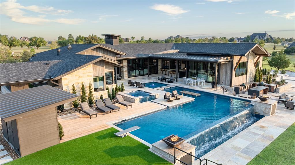 Less than an hour from Dallas, in Rockwall County—Texas’ smallest yet wealthiest county—this lakeside community draws those seeking space, privacy, and an elevated lifestyle. Set on over five acres within a gated subdivision, further secured by its own private entrance, this estate was crafted as the builder-developer’s personal residence and stands as a masterclass in Texas Modern design. Defined by clean architectural lines, organic textures, and expansive walls of glass, every detail is intentionally curated to blend sophistication with ease, offering enriched daily living and effortless entertaining.The 5,649 SF main residence showcases a gourmet kitchen and grand living area anchored by a striking linear stone-framed firebox, where views spill seamlessly outdoors. A dedicated fitness and wellness space opens directly to fresh air and poolside vistas, creating harmony between activity and retreat. From the upper level of the 1,486 SF two-story guest house-design studio, gather next to the fireplace and enjoy sweeping views of the estate and its grounds. The property also includes a 1,497 SF garage with workshop—ideal for creativity, hosting, or collection storage.Outdoor living unfolds across multiple gathering spaces, from expansive covered patios and full kitchens designed for celebrations to sleek lounging areas by the infinity-edge pool with in-pool bar seating. Play pickleball on your private court, watch the kids bounce on the in-ground trampoline, or wander to the private pond where casting a line offers simple joy. Take a ride by horse or ATV on trails within the subdivision. As the sun sets, gather around a fire pit nestled beneath manicured trees by the creek, sharing stories under the Texas sky.This is more than a home—it’s a luxury lifestyle designed for connection, recreation, and retreat. With Dallas less than an hour away, every convenience is within reach while you revel in the privacy of your own sanctuary.
