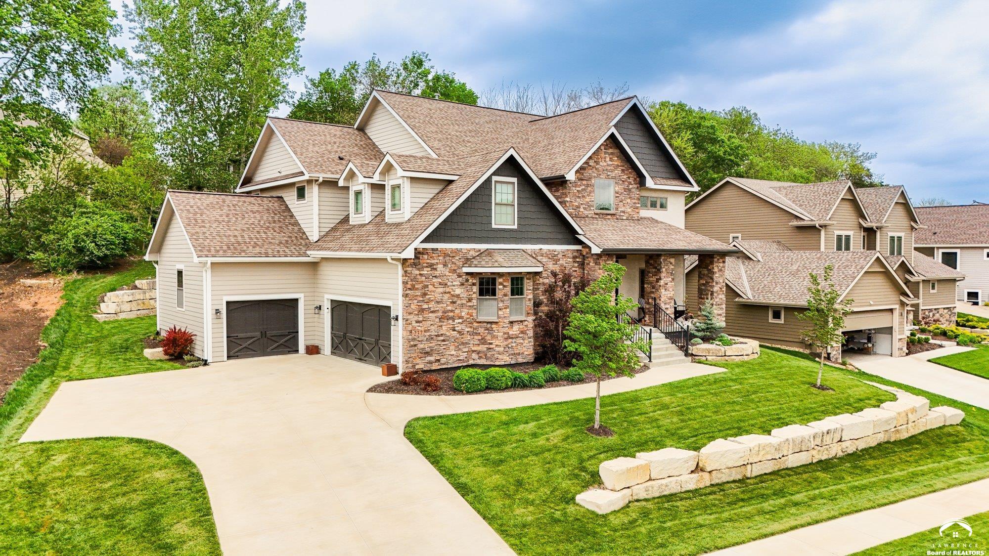 An incredible opportunity to own this one-owner home showcasing quality craftsmanship and thoughtful design throughout   From the welcoming front porch to the soaring two-story living room, this home makes an immediate impression. The main level offers true convenience with a spacious primary suite, dedicated office, and laundry.  The expansive living room is anchored by a stunning floor-to-ceiling stone fireplace and dramatic ceilings that fill the space with natural light. A beautifully curved staircase adds architectural character and leads to the upper level featuring three additional bedrooms, two baths, a bonus finished space, and a walkway overlooking the main living area below.  Designed for seamless entertaining, the screened back porch creates a private retreat complete with its own fireplace, space for an outdoor TV, and an adjacent covered patio which is perfect for year-round indoor-outdoor gatherings.  The finished basement adds exceptional versatility with a tiled wet bar area featuring a sink and full-size refrigerator, a fifth bedroom, additional bathroom, and abundant storage space.  This thoughtfully designed home offers comfort, functionality, and timeless style. If you’ve been waiting for the right opportunity, this is it. Schedule your private showing today.