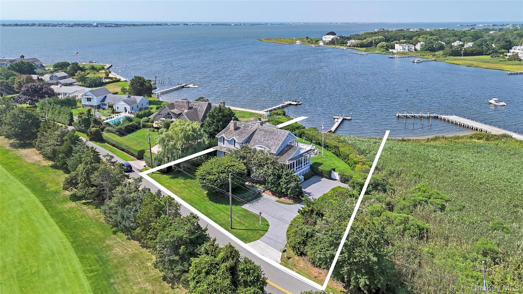 Welcome to elegant waterfront living at 69 Shore Road, Westhampton, NY. This exquisite 3,400+/- square foot residence offers a harmonious blend of modern luxury and serene natural beauty. With five bedrooms and three and a half bathrooms, this turn-key home boasts upgraded smart technology features including internet outdoor lighting, remote shades, & outdoor Sonos speakers, ensuring a seamless living experience. Inside you'll discover expansive water and sunset views that captivate from every angle. The main level provides a formal living area, enhanced by an inviting fireplace, a large screened in porch, separate den/media room with pocket doors for privacy, and a spacious gourmet kitchen equipped with Wolf, Viking, & Bosch stainless steel appliances. Upstairs, the primary suite, with its private waterside balcony, & en-suite bath. Down the hall sits four guest bedrooms with two hall baths and a bonus sitting/media area. Outdoors, enjoy the secluded backyard, perfect for entertaining or relaxation. An outdoor kitchen with grill, warmer, fridge, hot & cold sink, along with multiple decks, a refreshing pool, and a 180-foot floating boat dock & dock box. The property overlooks the picturesque Westhampton Golf Course, adding to its allure. This home is designed for comfort and style. Discover unparalleled waterfront living today.