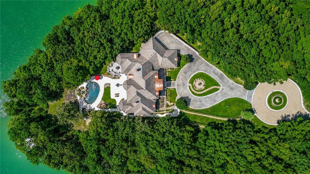 Located in the gated community of Riss Lake, this extraordinary estate offers a secluded setting where cobblestone-style streets lead you home to grand architecture, exceptional scale, and resort-style living. Situated on 1.22 acres and offering over 11,000 square feet across three levels, the home makes an unforgettable first impression with its stately brick exterior, circular drive, and dramatic entry.Inside, soaring ceilings, expansive windows, intricate architectural details, and a showstopping staircase with glass railings connect the impressive living spaces. The main level was designed for grand entertaining while remaining inviting for everyday living. The beautifully appointed kitchen features extensive custom cabinetry, a large center island with seating, granite countertops, and stainless steel appliances. Multiple gathering and dining areas provide incredible flexibility while walls of windows fill the home with natural light.The primary suite is a destination of its own with generous proportions, a fireplace, sitting area, and beautiful architectural ceiling details. Multiple bedrooms, baths, offices, and flexible-use rooms span all three levels, including several spaces that could potentially be converted into additional bedrooms to accommodate a variety of needs.The lower level takes entertaining to another level with expansive recreation and gathering areas, a full bar with abundant seating, an additional kitchen, and direct access to the outdoor living spaces.Outside, the private backyard feels like your own resort. A spectacular in-ground pool is surrounded by extensive patio space, lush landscaping, and multiple areas for relaxing or entertaining. From the dramatic architecture and incredible scale to the secluded setting and resort-style backyard, this is a property that simply has to be experienced in person.