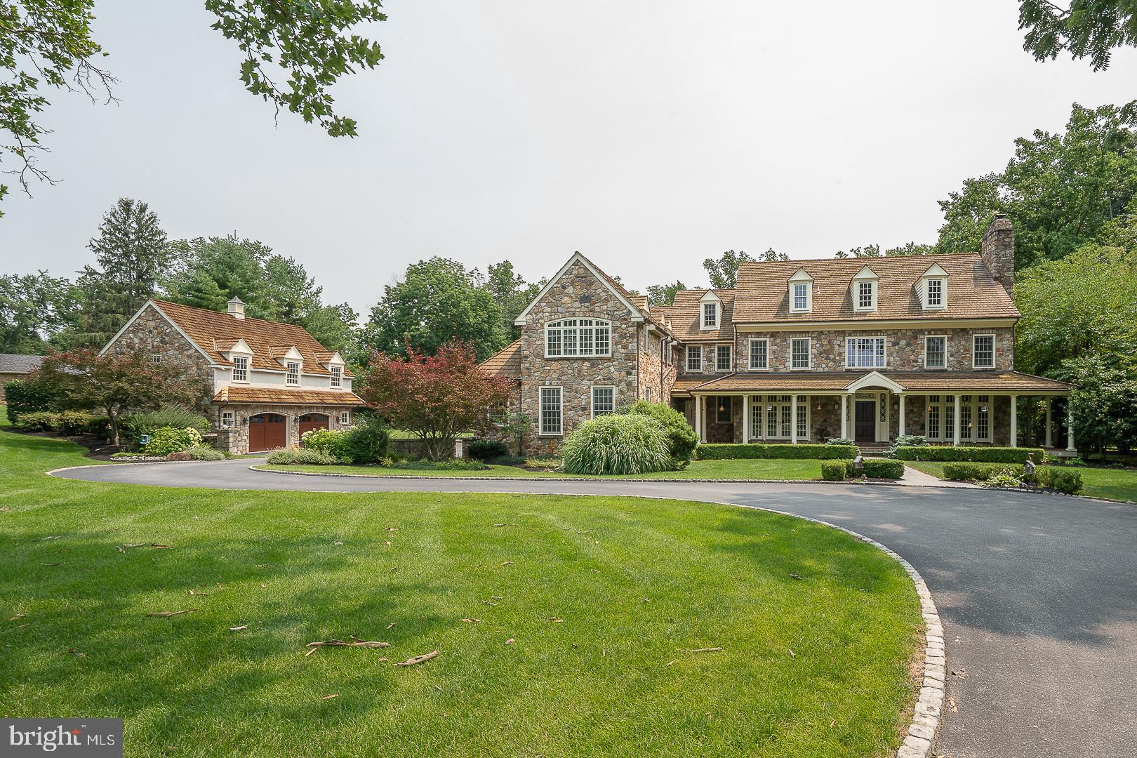 Welcome to 2048 Buttonwood Road, an exceptional country estate gracefully set on 1.9 professionally landscaped acres in one of Easttown's most coveted locations. Offering the perfect balance of timeless architecture, exceptional craftsmanship and modern comfort, this extraordinary residence encompasses over 8,000 square feet of living space with 6 Bedrooms, 7 full Baths, 2 half Baths, 5 fireplaces and a finished Third Floor plus  a professionally finished Lower Level. From the moment you arrive, the home's stately presence and impeccable grounds set the tone for what awaits inside. A newly reconstructed Azek front porch (2025) leads to a dramatic front-to-back Foyer with soaring ceilings, rich hardwood flooring, elegant arched openings and exquisite custom millwork. Designed with effortless entertaining and comfortable family living in mind, the Main Level flows beautifully from one space to the next. The formal Living Room, anchored by a marble fireplace, and elegant Dining Room each open to the front porch through atrium doors, while a well-appointed Butler's Pantry with beverage refrigerator, wet bar, glass-front cabinetry and wine storage provides exceptional convenience for hosting. The Gourmet Kitchen offers custom furniture-style cabinetry, an oversized center island, farmhouse sink, Viking commercial range, decorative tile backsplash with pot filler and a light-filled Breakfast Room overlooking the breathtaking rear grounds. Just beyond, the spectacular vaulted Family Room showcases hand-hewn wood beams, custom built-ins, a floor-to-ceiling stone masonry fireplace and an impressive wall of windows and doors that seamlessly connect the interior to the outdoor living spaces. A richly paneled cherry Study offers a quiet work-from-home retreat, while a versatile Flex Room is ideal as a playroom, craft room or second office. A Mudroom and two Powder Rooms complete the Main Level. Upstairs, the luxurious Primary Suite is a peaceful sanctuary featuring hardwood flooring, a fireplace, custom built-in wardrobes, two professionally designed walk-in closets and a luxury Bath with radiant heated floors, dual granite vanities, deep soaking tub, oversized shower and private water closet. Four additional Bedrooms each feature their own en-suite Bath, including one with a private Sitting Room, while a spacious Laundry Room completes the Second Floor. The finished Third Floor provides an ideal guest, au pair or in-law suite with a spacious Bedroom and full Bath. The professionally finished Lower Level extends the home's exceptional living space with a generous recreation and entertainment area centered around a stone fireplace, a dedicated fitness room, a beautifully finished full Bath, abundant storage and plumbing already in place for a future wet bar. The resort-inspired outdoor living, designed for entertaining and relaxation, is truly exceptional and features an Armond inground pool and spa, expansive maintenance-free decking, a wood-burning stone fireplace and Three Season Room, completely rebuilt in 2021 using Azek and LP SmartSide. Surrounded by mature landscaping and expansive lawn, the property offers remarkable privacy and a setting that feels like a private country retreat.  Add'l highlights include geothermal heating throughout, a whole-house generator, complete exterior painting (2023), complete interior painting (2026), an attached 3-car garage and a detached 2-car stone garage with partially finished space above, offering endless possibilities for a future home office, studio or guest quarters. Perfectly positioned within the award-winning Tredyffrin-Easttown School District and just minutes from the area's premier private schools, renowned country clubs, upscale shopping, fine dining and major commuting routes, this remarkable estate offers a rare opportunity to enjoy luxury living in one of the Main Line's most desirable settings.