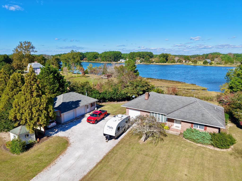 Enjoy peace, privacy, and scenic water views from this beautiful brick home on 3.09 acres, located just outside the charming waterfront town of Onancock. This single-level home offers 2 bedrooms, 1.5 baths, and 1,324 sq ft of well-designed space. Inside, you'll find a large great room with a brick fireplace, a cozy family sitting room overlooking the creek, and a spacious kitchen that flows into the dining area—perfect for entertaining. Each bedroom features two closets, and the main bath includes a jacuzzi tub, walk-in shower, bidet, and ample storage. The property also includes a 1-car attached garage, 2-car detached garage, and a large, tall carport ideal for boats or RVs. Experience the perfect blend of waterfront tranquility and small-town charm in this inviting Eastern Shore retreat.
