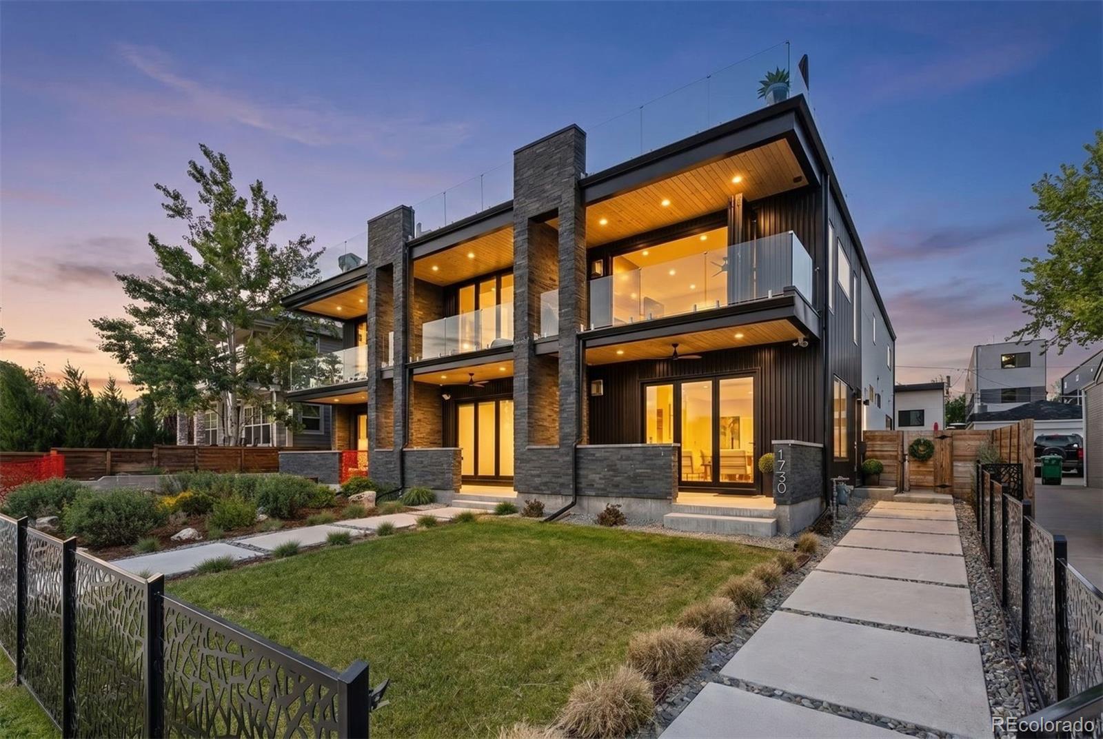 In a city where truly irreplaceable homes are exceptionally rare, 1730 Meade Street emerges as one of Denver’s most extraordinary contemporary residences — a trophy property defined by architecture, atmosphere, and an unrivaled connection to Sloan’s Lake and the Rocky Mountains beyond. Positioned on one of the most coveted blocks surrounding Sloan’s Lake, this striking five-bedroom, six-bathroom rowhome was designed to capture the drama of Colorado living from every possible vantage point. Expansive NanaWall doors create seamless indoor-outdoor living with multiple decks, patios, and rooftop spaces designed to embrace Colorado sunsets and a low-maintenance luxury lifestyle. Inside, carefully curated finishes, intentional sightlines, abundant natural light, and a stunning floating staircase define the home’s elevated modern design. The gourmet kitchen features professional-grade appliances, custom cabinetry, and refined entertaining spaces throughout. An elevator services all levels, while radiant heated bathroom floors add everyday comfort and sophistication. The luxurious primary suite offers panoramic views, expansive custom closets, and spa-inspired finishes. A versatile third-floor living space with wet bar and rooftop access functions perfectly as an office, guest retreat, or entertainment lounge with amazing views!! The lock-off basement apartment with 2 bedrooms/2 bathrooms/ full kitchen and private entrance provides ideal flexibility for guests, multigenerational living, or income potential. Complete with an oversized 2-car garage and located moments from Sloan’s Lake trails, acclaimed restaurants, breweries, coffee shops, and Empower Field, this is a rare opportunity to own an irreplaceable trophy property in one of Denver’s most desirable locations.