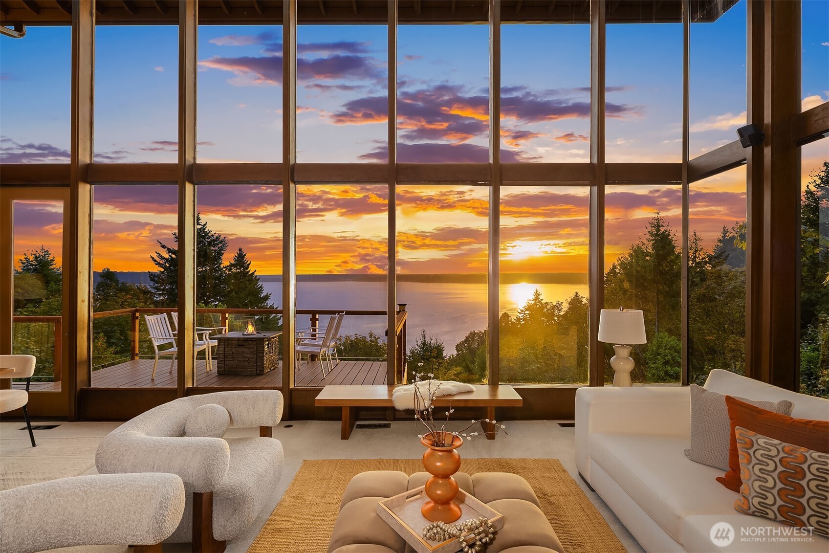 Ralph Anderson Haven // Designed by renowned architect Ralph Anderson, this exceptional home sits on a 35,000+ sqft double parcel with protected panoramic views of Puget Sound, the Olympics, and Mt. Rainier. Thoughtfully hardscaped with a waterfall and surrounded by lush greenery, it offers a private, tranquil oasis. Inside, cedar tongue-and-groove ceilings, a soaring 15’ stone fireplace, and floor-to-ceiling windows create a warm, light-filled retreat. Expansive decks with custom lit glass railings are perfect for entertaining. Lofted primary suite offers stunning views, a skylit ensuite with sauna, discrete mirrored TV, and private hot tub. The lower level includes a large flex space, private deck, and three light-filled bedrooms.