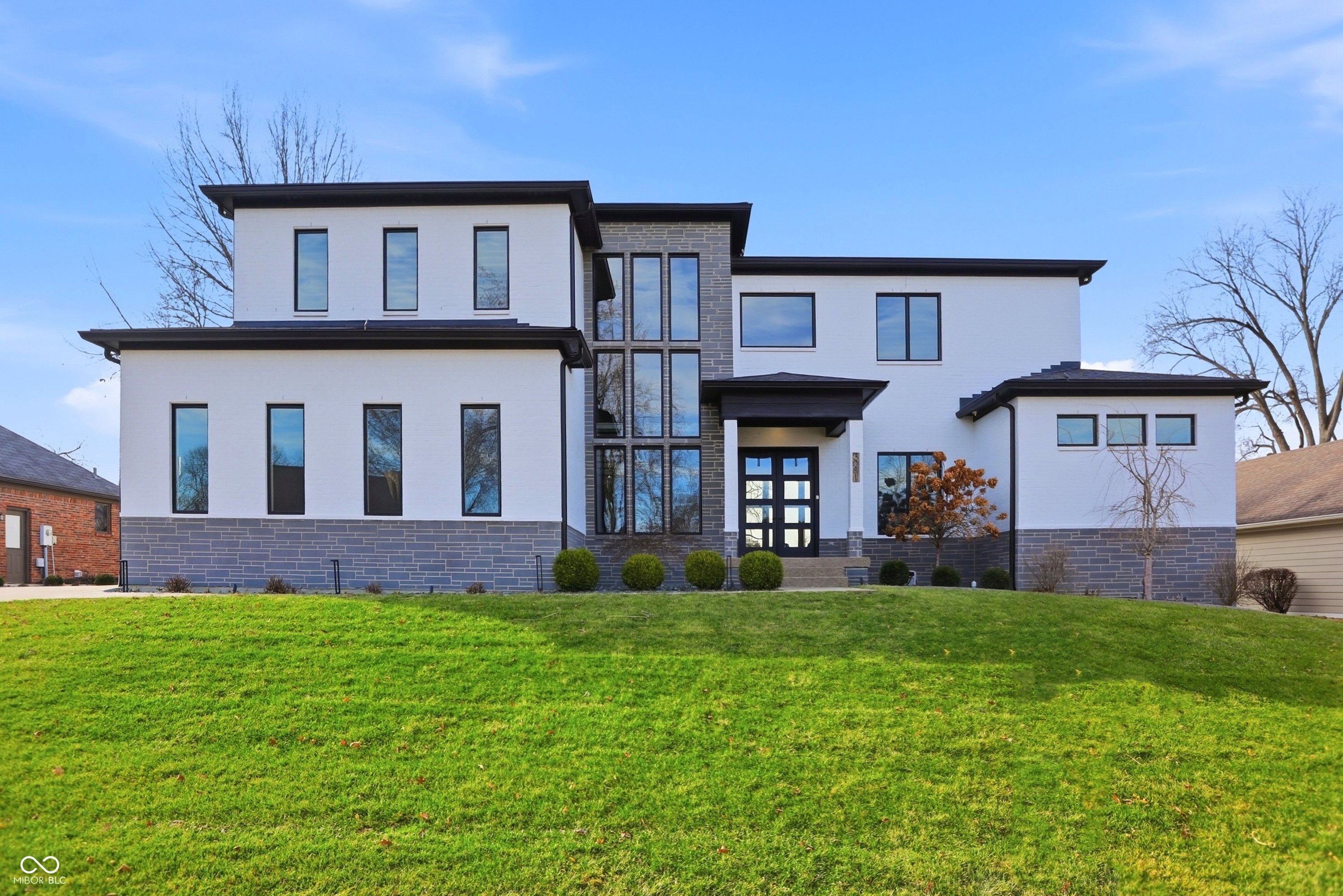 This home is an absolute showstopper-a modern masterpiece tucked into a neighborhood with actual character. It's rare to find a 2020 build that offers both the privacy of a mature, established community and the prestige of being on the only private golf course in Johnson County. The main-level owner's suite isn't just a bedroom; it's a private wing designed for ultimate rejuvenation. Start your day at the built-in coffee station and end it by the glow of the bedroom fireplace or evening overlooking the 18th fairway. A lavish spa like bathroom leads to a custom-milled walk-in closet that rivals high-end boutiques. Step out onto a private patio featuring a gas fireplace and retractable screens with clear winter inserts, allowing you to enjoy the golf course views 365 days a year. The heart of the home features soaring ceilings and an open-concept layout bathed in natural light. The Great Room: A floor-to-ceiling natural stone fireplace serves as a breathtaking focal point, complemented by engineered hardwoods and designer contemporary lighting. Culinary & Hosting: The chef's kitchen flows seamlessly into the dining area and features a massive walk-in pantry and a dedicated main-level wine room for the connoisseur. Purposeful Mudroom: A full bath featuring a custom dog-wash station and personalized lockers ensures the home stays pristine. The massive four-car garage is a hobbyist's dream, currently featuring an indoor basketball goal. Above the garage, discover a secluded professional office with its own private entrance-offering total separation from the main living areas for focused productivity. Entertainer's Backyard: The covered outdoor living space features an outdoor kitchen with multiple cooking options, a TV lounge, and motorized retractable screens. Upper Level: A sprawling loft connects three spacious bedrooms (one en-suite) and two full baths, all featuring premium custom millwork in the closets.
