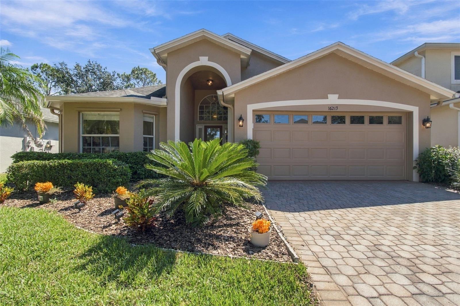 Welcome to the popular Mayfair community in Tampa Palms, where this well-designed Jacaranda floor plan offers four bedrooms, three bathrooms, and nearly 1,900 square feet of living space. Soaring cathedral ceilings and large windows fill the home with natural light, while upgrades appear throughout. Finishes include 17-by-17-inch ceramic tile in the entry, kitchen, dining room, bathrooms, and laundry room, plus laminate flooring in the great room. The kitchen features granite countertops, a coordinating backsplash, maple cabinetry with 42-inch upper cabinets, a convenient recipe desk with glass-front cabinets, a breakfast bar, and stainless steel appliances, including a French-door refrigerator, smooth-top range, built-in microwave, and dishwasher. Additional highlights include 5¼-inch baseboards, a paver driveway and walkway, a glass front door with sidelights, recessed lighting, and more. Relax on the extended screened lanai and enjoy the private wooded setting. Mayfair is a maintained community that provides full grounds care. The home is next to Club Tampa Palms, a short walk from A-rated Chiles Elementary School, and close to shopping, dining, and recreation. USF, several hospitals, I-75, I-275, and Busch Gardens are also just a short drive away. Well maintained and move-in ready, this home is ready to welcome its next owner.