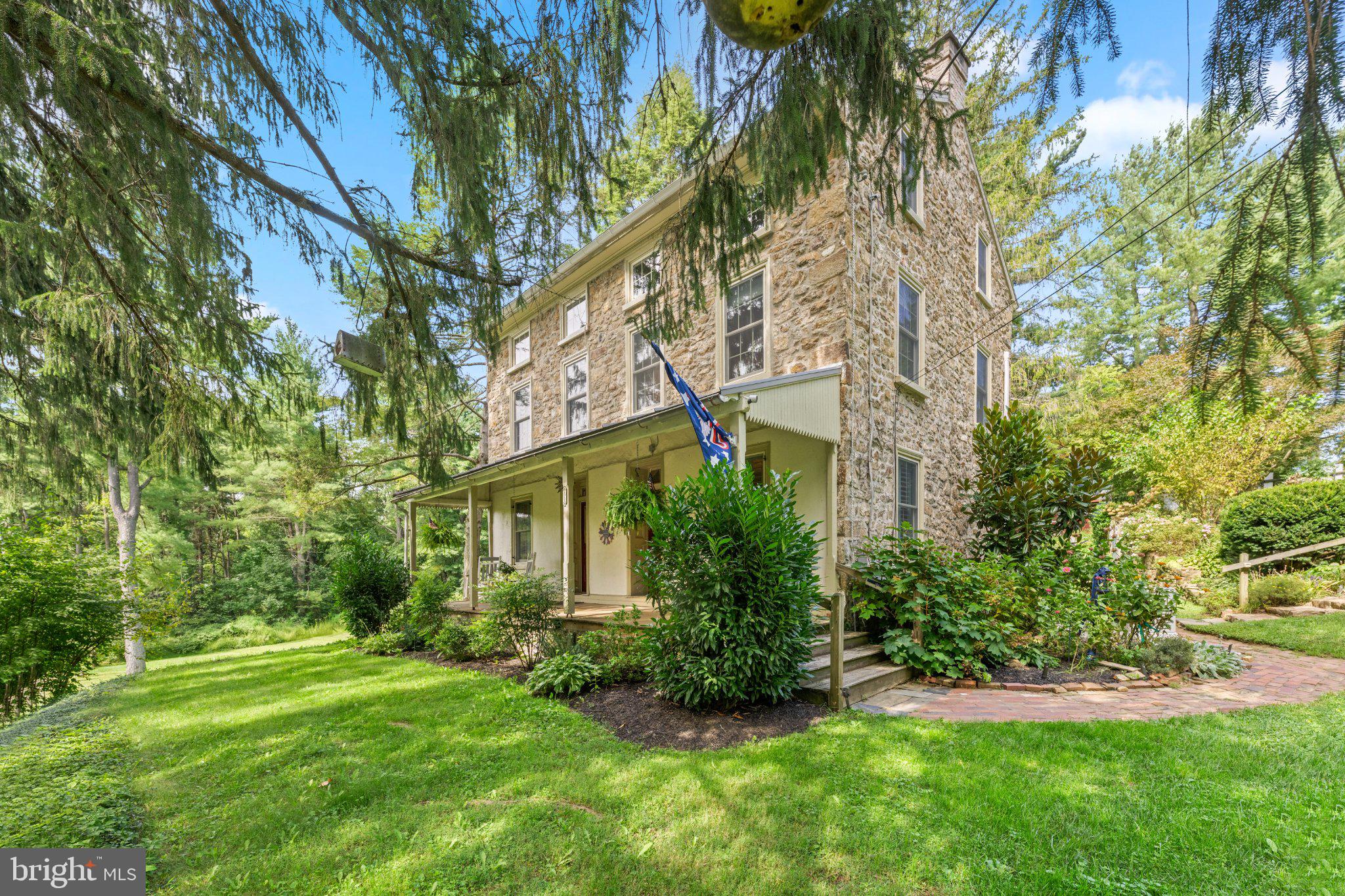 Welcome to this quintessential circa 1850 Chester County Farmhouse situated on a bucolic and picturesque 1.4 acre lot.  The home is rich in history with its classic fieldstone construction and enduring craftmanship.  From the warm and inviting covered from porch, step into the spacious living room with wood-burning stove with stone hearth & back and beamed ceiling.  To the right is the gracious light filled dining room with a distinctive fireplace.  The adjacent butlers pantry offers old world charm with a classic built-in.  The generous sized updated kitchen highlights an exposed stone wall, bead board & beamed ceiling, a wood burning stove, open shelving, built-in storage and access to a private patio, brick walkway and lush gardens.  A quaint powder room and mudroom are on this main level.  The oversized primary bedroom is on the second floor along with two additional bedrooms and a full bath.  The third level offers two large bedrooms, another full bathroom and a storage room. This exceptional home exudes timeless elegance with its old world charm, period details, preserved hardwood floors, deep windowsills, millwork, clawfoot tubs, stone elements and more.  The new custom oversized detached 3-car garage is built-out for adding an electric car charger and also boasts a 630 SF finished loft area above with heat, AC, ethernet and wi-fi access. Additional notable features;  new custom Anderson windows throughout; installation of central air along with gas propane heat (tank is owned);  generac propane fed generator w/ automatic transfer switch that feeds the entire property including garage, AC, pumps, etc;  reinsulation of the main house roof;  custom plantation shutters installed;  newer washer, dryer and dishwasher.  This idyllic rural setting, offering lush surroundings, mature landscaping, and expansive grounds with multiple outbuildings is where historic character and country living come together.