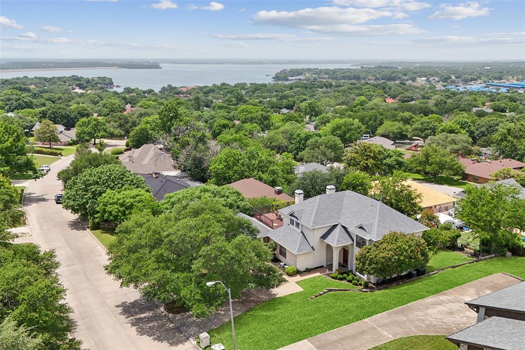 This beautifully updated three-story traditional is tucked away on a hard to find lot in the sought-after Lake Country Estates - offering a secluded retreat surrounded by mature trees & nature-inspired surroundings—all just minutes from city amenities. This home features 4 spacious bedrooms, 4.5 bathrooms, complemented by wood flooring in the main areas, and walls of windows that bathe the interior in natural light while framing breathtaking sunset views over Eagle Mountain Lake. Three unique outdoor areas include: a newly remodeled, extra-large balcony deck with Italian-style wrought iron banisters & 25-year engineered composite pavers, a shaded walkout patio off the basement, and an outdoor area is a full-size wooden deck overlooking the backyard with a gas tap for an outdoor kitchen, also with views of the lake! The walkout basement, freshly updated with new paint, flooring, drywall, and carpet, includes a half bath with new fixtures, perfect space for a rumpus room, media-game room, or bring your HGTV dream ideas to life! This chef's kitchen boasts quartz countertops, Italian designer tile mosaics, and an oversized walk-in pantry, while the expansive main living room offers skylights & a welcoming WBFP. Highlights include a separate home office with French doors, and an oversized laundry room with dual sinks. Upstairs, the owner’s suite provides private access to the balcony with lake views. 2 additional bedrooms, 1 offering its own private ensuite & the other bedroom has direct balcony access. Large U-shaped driveway with space for 3+ additional vehicles, an extra-large 2 car garage with built-in shelving, pegboard walls, and ample storage with both a large outdoor shed & a smaller utility shed. Updates: A new HVAC system (2024), new ductwork, roof (2022), vinyl double-pane windows, piered main slab, recently painted & stained the back deck, fresh landscaping & French drains. This one-of-a-kind home is the perfect backdrop for elevated lake living!