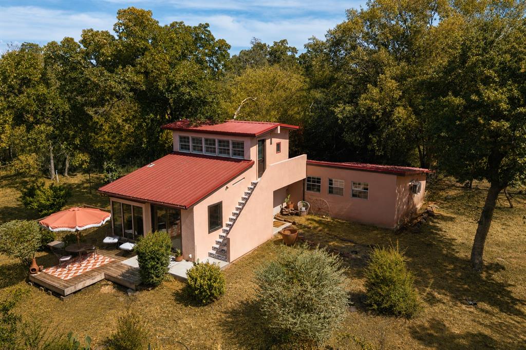 The possibilities are endless with this beautiful and unique property. Sitting on 3.6 wooded acres, this Santa Fe style home offers peace, tranquility and seclusion that will leave you in awe that such a place exists in the middle of the city. Tucked back on a winding gravel road, this home can not be seen from the main road. There are multiple sites within this property to build your dream home and keep the existing one as a guest house, studio, or income producing property. There are several outbuildings including a small metal shed, a wood shed and a huge open air barn/shop. There is even a small pond between the house and barn. The house is on well water and septic and is heated/cooled by two mini-split units. Roam the property and you'll find a storm shelter, water spickets throughout and even a sweat lodge hidden at the far west side of the lot. The interior of the home was renovated last year and is an open concept one bedroom one bath with a separate loft space.  Practically everything is new- the flooring, cabinets, counters, plumbing, fixtures, appliances etc. And with a metal roof you're set for years to come. The vaulted ceiling in the living room and floor to ceiling windows make the room feel spacious and bright. The view from every window will provide you with nature, privacy and likely a few deer. Follow the hall back to the large bedroom with cozy wood finishes and ample storage. The bathroom is not to be missed, as you'll love the sunken shower with huge picture window that allows you to feel at one with nature. This place is truly one of a kind and must be experienced in person. Schedule your showing today and don't miss your opportunity to purchase a rare in town acreage.