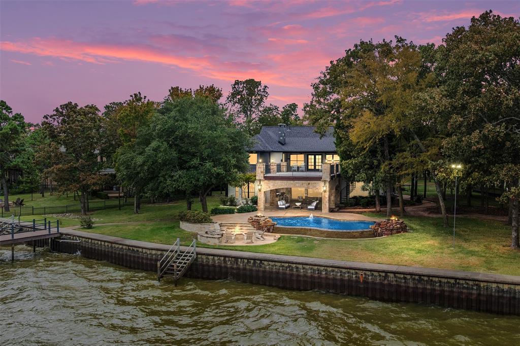 Welcome home to a beautifully revived waterfront estate in gated Pinnacle Club—situated toward the point of a peninsula on one of the community’s most desirable streets. Thoughtfully updated with new exterior paint, windows, flooring, lighting, ceiling fans and remodeled baths with quartz countertops, the open floor plan flows from a Thermidor-equipped kitchen with quartzite surfaces into generous living and entertaining spaces, then out to an infinity pool with dramatic fire features, a cozy outdoor fireplace, and a covered outdoor kitchen appointed with a wood burning fireplace, grill, oversized burner, Big Green Egg, abundant lighting, ceiling fans and LAKE VIEWS TO DIE FOR. Upstairs, a central game room is surrounded by five bedrooms, two of which open directly to a huge terrace overlooking the water, providing endless WATER views and light. With a large boat dock and upper deck, near-peninsula privacy, and access to Pinnacle Club’s 18-hole championship golf course, full-service country club dining, pool, tennis and new pickleball courts, this rare lakefront home delivers resort-caliber amenities and everyday waterfront living.