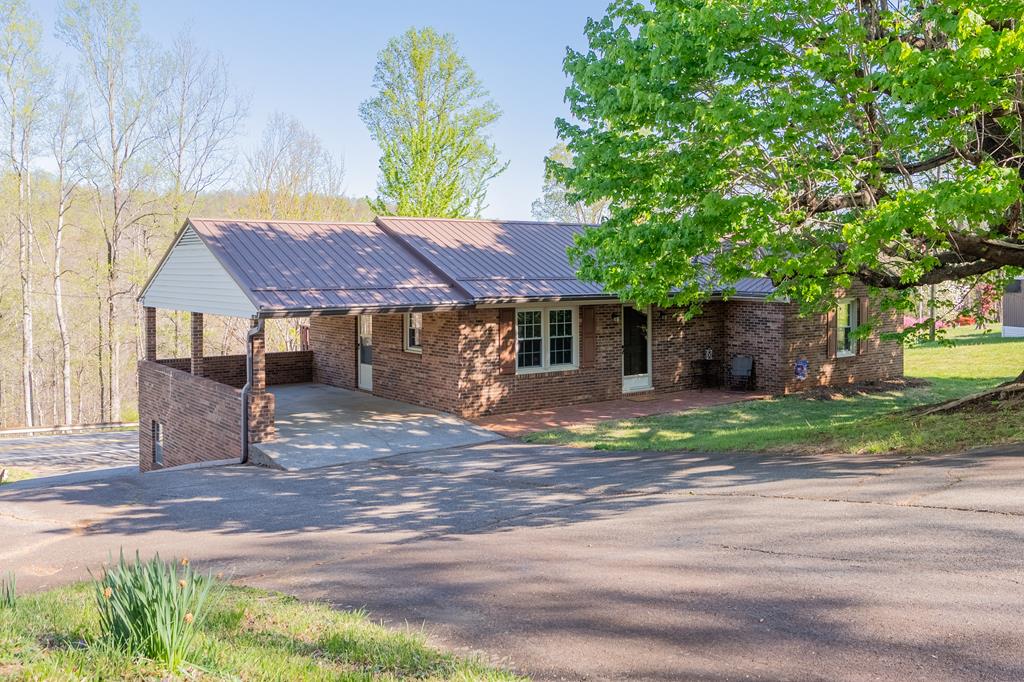 Discover this well-maintained 3-bedroom, 2-bath brick ranch nestled in the scenic beauty of Stuart, VA. Conveniently located near Woolwine, Stuart, and Martinsville, this home offers both comfort and accessibility. Inside, you'll find a nicely updated kitchen, replacement windows, fresh interior paint, and new carpet—making it truly move-in ready. The home also features central A/C and a durable metal roof for added peace of mind. The partially finished basement provides valuable additional living space, complete with a single-car garage—perfect for a family room, home office, or recreation area. Outside, enjoy the convenience of an upper-level carport that doubles as a great space for entertaining. Additional highlights include a water filtration system and backup propane gas heat, offering both efficiency and reliability. Whether you're searching for a starter home, investment property, or a comfortable place to retire, this property checks all the boxes!