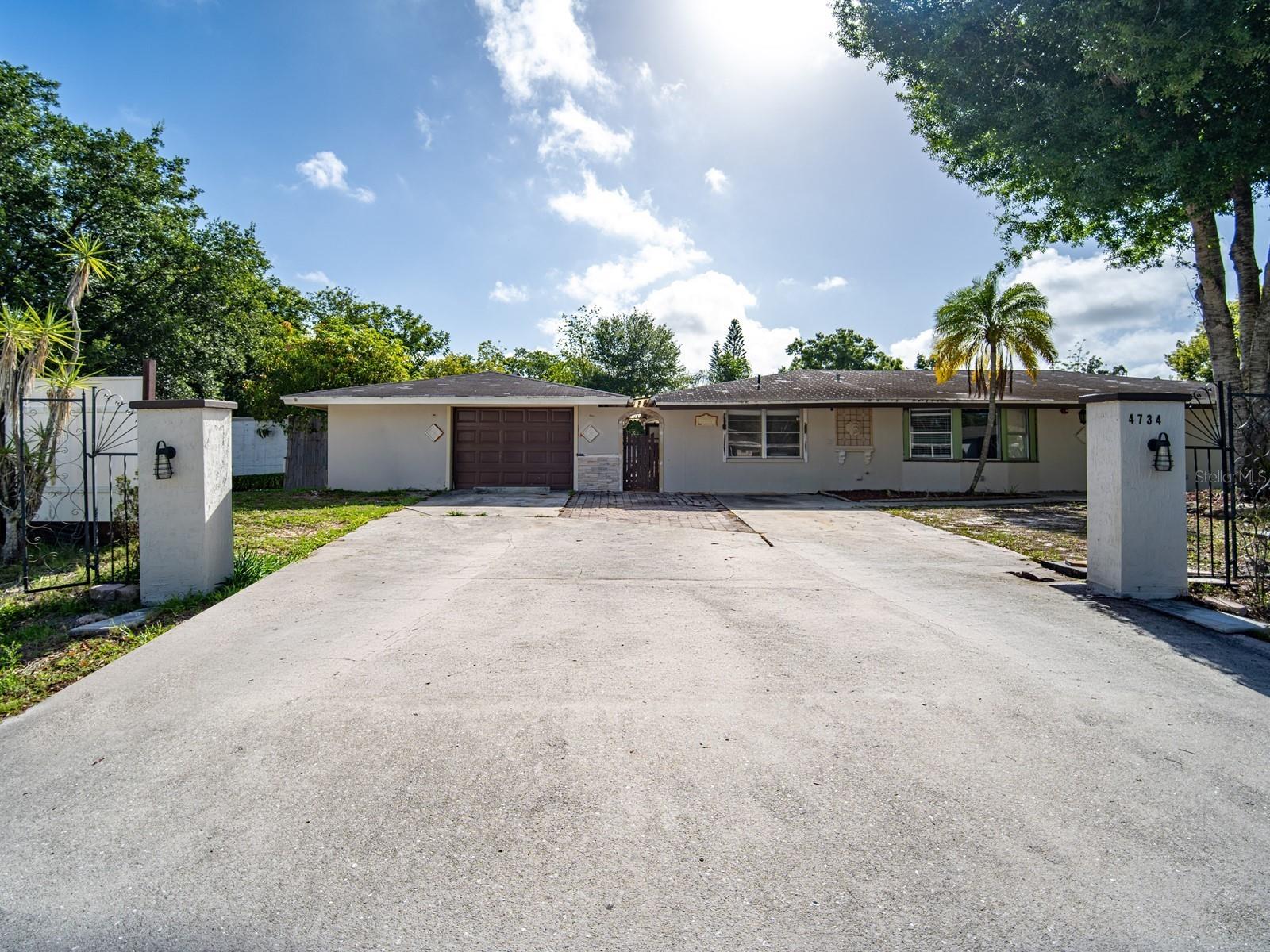 4734 Delmonte Avenue, Sarasota, FL — Investor special and fixer-upper on an oversized double lot in a non-deed-restricted Sarasota neighborhood with no HOA. This 4-bedroom, 3-bathroom home features a dual primary floor plan with two en suite bedrooms, each with a private bath, a bay window living room, and a family room opening to a covered back porch and brick paver patio, plus a covered pavilion that creates a shaded outdoor retreat — the kind of space that could get used year-round in the Florida climate — all set behind a wide driveway with paver accents, connected with a breezeway and arched entry. The home also retains several ornamental architectural details — decorative elements, arched openings, and Mediterranean-influenced touches — that, with the right restoration effort, could be brought back to life and lean fully into a Spanish Mediterranean aesthetic that suits the Sarasota region beautifully. The property’s most compelling asset is a detached accessory structure with its own eat-in kitchen, living area, bedroom with a closet, full bath with a walk-in shower, private back patio, and a separately fenced yard. The building will require a thorough rehab and the addition of climate control before it can function as a guest cottage, rental unit, or additional living space — but the layout and footprint are already there, making it a strong candidate for the right buyer willing to put in the work. Alternatively, it could be converted back into a garage and workshop or repurposed in a number of other ways, depending on your needs and interests. The double lot provides ample room for a future pool or expanded outdoor living, and the absence of deed restrictions means boats and RVs are welcome on-site with no approvals required. Conveniently located near Longwood Park, Nathan Benderson Park, University Town Center, and the new Mote Marine Aquarium, with quick access to I-75, Sarasota International Airport, Downtown Sarasota, and the Gulf Coast beaches — this is a property with strong locational fundamentals and significant upside for the right buyer. Offered strictly as-is — which means what you see is what you get. Ready for a buyer who sees the opportunity. Per county records, the main house is 4-bed / 3-bath / 1,762 sq ft, air-conditioned. The 572 sq ft accessory structure is listed in the MLS both as a 2-car garage and as an in-law suite for search purposes, and is reflected in county records as 2 bed / 1 bath with no A/C — included in total recorded square footage. Buyers should verify all details independently.