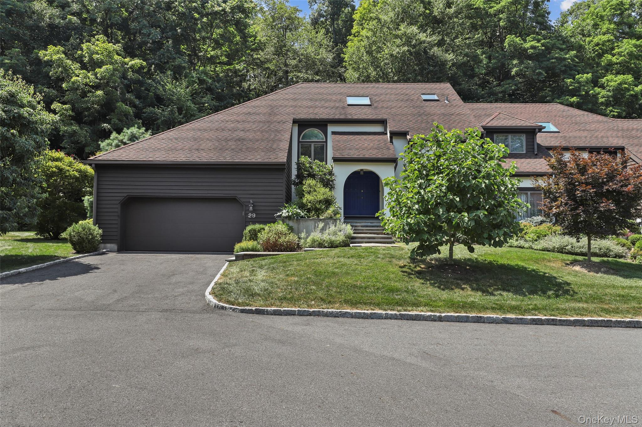 Welcome to 29 Cotswold Dr, a meticulously maintained single-family townhouse in North Salem, blending modern sophistication with serene natural beauty. Lovingly owned by the same family since the late 1980s, this home offers a rare first-floor primary suite for effortless single-level living, plus a second bedroom on the top floor with its own private bathroom.

Inside, original quarter-sawn oak floors with a natural finish flow throughout, complemented by a cozy wood-burning fireplace in the living area, perfect for relaxing evenings. Anderson sliding glass doors (installed 2022) open to a private deck, framed by wild raspberry vines cascading over a stone wall, creating a tranquil retreat. The professionally landscaped lawn showcases a rare yellow magnolia “Lois” shade tree, developed by the Brooklyn Botanical Gardens, alongside dogwood, Japanese maple, and pine trees. Vibrant flower beds with hydrangeas, peonies, and more add seasonal charm. The property backs onto protected, densely wooded forest land, part of North Salem’s 2009 open-space plan, ensuring privacy and natural splendor.

The remodeled kitchen (2008) is a chef’s dream, featuring handmade ceramic backsplash tiles from Pratt & Larson, a checkerboard floor of white marble and black granite tiles, and a custom stainless steel countertop with a seamlessly braised Blanco sink by Danbury Sheet Metal. Black quartz composite countertops and custom Omega Cabinetry with quarter-sawn oak doors and Sun Valley Bronze pulls offer both style and functionality. Bosch appliances and a custom window seat with cushions complete this inviting space. Elegant Tech Lighting pendant fixtures illuminate the foyer and dining area, enhancing the home’s warm ambiance.

Additional features include a spacious two-car garage, a full basement for ample storage, and thoughtful updates throughout. With its refined craftsmanship, serene setting, and practical amenities, 29 Cotswold Dr is a rare gem in North Salem. Schedule your private tour today to experience this exceptional home!