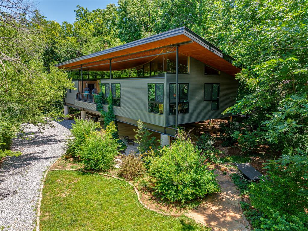 This custom “tree house” is built on concrete piers that were sunk 21 ft into the strong shale & rise 10 ft above the ground. The American Institute of Architects Award Winner of the 2021 People’s Choice Award. Home is on .61 acres & is located 1 mile from the University of Oklahoma. Just past the Automatic Liftmaster Gate, you are greeted with stone-lined nature trails & a stage. At the base of the stairs is a waterfall feature & an alternative steel ramp. This highly efficient residence has extra insulation in the walls/roof, energy-efficient windows, and a wood-burning stove that heats the whole house. The living room has a custom, built-in sofa & stunning views. Primary bedroom has floor-to-ceiling windows & heated floors that extend into the primary bath w/double shower head & Toto Washlet bidet. Kitchen has 18 ft marble countertop, gas range, Pantry/appliance closet, Ample storage, wall oven, and coffee bar w/ sink. Dining has a built-in custom dining table. Flanking the dining area are 2 cozy nooks(sleeping berths) w/ lighting, outlets, & privacy curtains. The guest bath has a pedestal sink, a pocket door, & tub/shower combo. Laundry room w/ large storage area. Large outdoor living area/balcony has privacy & lots of scenery. Under the house is a parking/activity area. Carport at gate.