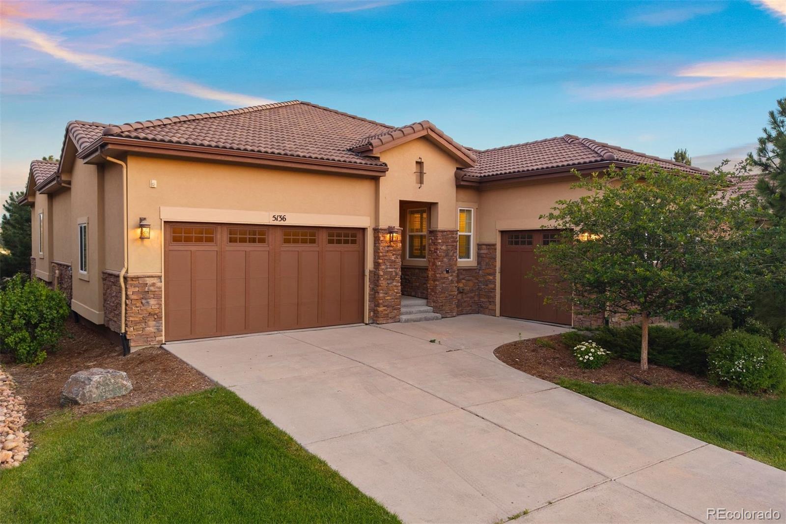 Ranch style living finds its ideal setting in this detached single-family home, tucked within the most desirable gated golf community south of Denver. Brand new wood floors run through the main level, where 2 bedrooms, including the primary suite, share space with a private office, all wrapped in a light-filled, open floorplan. 2 additional bedrooms occupy the garden-level basement below. The Village at Castle Pines surrounds two exclusive golf courses with towering pines and mountain views, just steps from the Village Lake Fitness Center and delivering a serene lifestyle that's genuinely hard to match. Mature pines shade a quiet lot, with HOA maintained landscaping doing the work of a lawn mower, so the three-car garage stays free for a golf cart. 10-foot ceilings span the main-level, with bay windows drawing natural light into every space from the entry foyer to the living areas. The formal dining room flows directly into the kitchen, where stainless steel appliances, dark wood cabinetry, a walk-in pantry, and a granite island with seating anchor ample prep space. A casual eat-in area sits adjacent, with a walk-out to the spacious back deck. The great room centers on a gas fireplace with built-in surround sound. The main-level primary suite accommodates a king size bed with a luxurious ensuite featuring a granite dual-sink vanity, soaking tub framed by a window, glass-enclosed walk-in shower, massive walk-in closet, and private water closet. A second bedroom, dedicated laundry room, and private office with French door entry and built-in bookshelves round out the main floor. The secure garden-level basement has a bright, large recreation space with 9-foot ceilings, and two additional bedrooms that are flexible for guests, a gym, or hobby use. The Village at Castle Pines offers miles of trails, a pool, and a fitness center within the gates. Castle Rock's shops and restaurants are just minutes away, and easy I-25 access means Denver is just within reach.