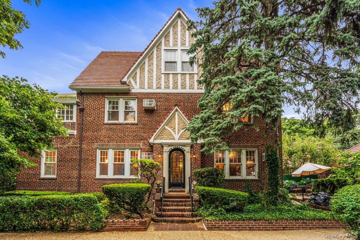 Welcome to this gracious semi-attached brick residence in the sought-after Forest Hills Gardens vicinity offering four bedrooms, three baths, and private two car garage. Filled with original plaster moldings and classic details, the home features a grand-sized living room with an adjoining piano room, a formal dining room, and a large eat-in kitchen with two separates entrances. The kitchen opens to a beautiful garden patio. creating a wonderful space for outdoor dining and entertaining. The second floor offer a massive primary bedroom with an enchanting, vaulted ceiling sunroom, a second spacious bedroom, and a full bathroom. The third floor includes the large bedrooms, another full bath, and a full-height unfinished attic with tremendous potential for future expansion or storage.The basement level features an original wet bar with copper sink and large wine cellar/storage room/workshop with a window. Open room perfect for entertainment!A rare combination of generous room sizes, original character, flexible living space, and two-car garage that can be converted to a family room makes this wonderful opportunity in the heart of Forest Hills.