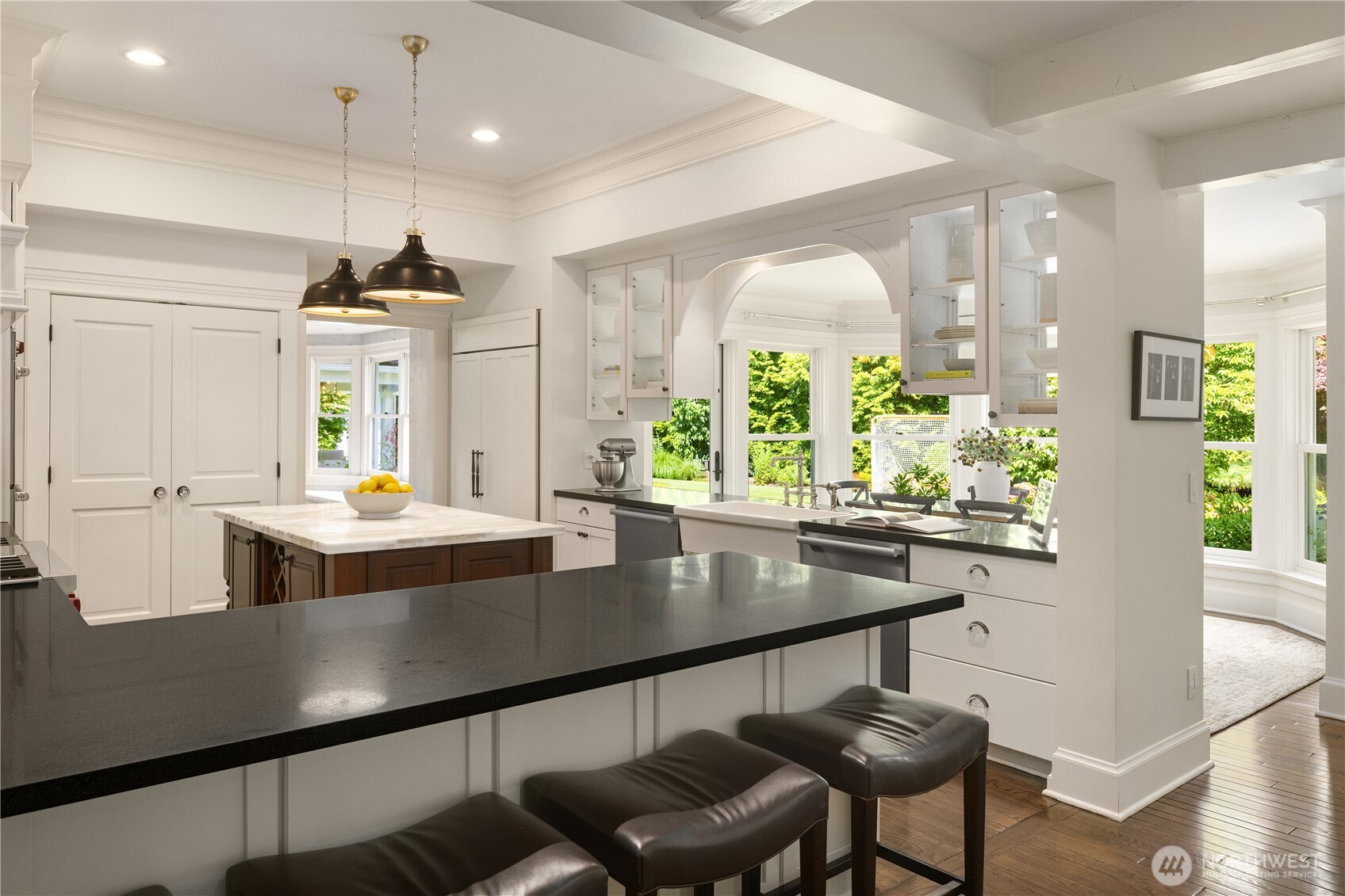 Kitchen bar seating overlooks the sunlit breakfast nook beyond