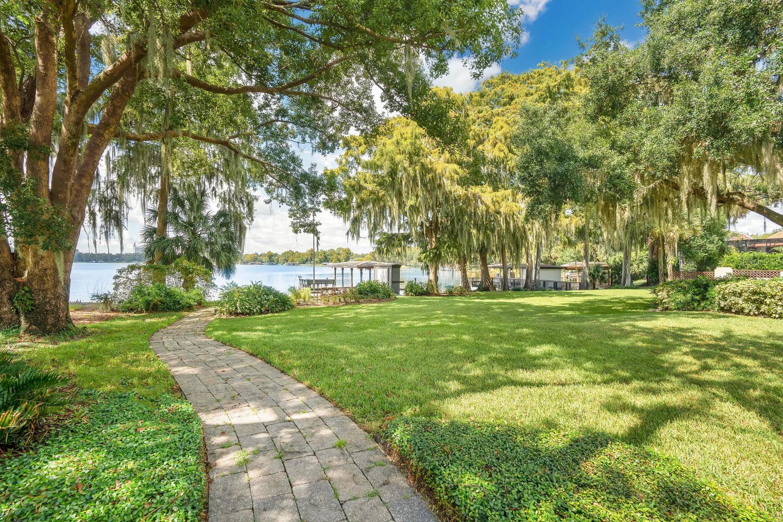Just Listed ~ Stunning lakefront home in Winter Park that has been completely remodeled and offers 4 bedrooms, a bonus room, and guest apartment!  This home is exquisite from top to bottom and features elevated ceilings, crown moldings, designer fixtures and wall coverings. Large picture windows overlook Lake Sue from the living room, dining room, and kitchen. The kitchen is gorgeous and offers chef-grade appliances, a large center island, plenty of soft-closed cabinetry for storage, and an open-concept layout for inclusive entertaining. French doors open off the family room to seamlessly blend the indoor/outdoor living space. A covered lanai with outdoor kitchen overlooks the beautiful, resort-inspired, heated pool and spa, multi-level summer terrace with gardens, and the custom 3-hole putting course. Back inside, located on the 2nd floor, the primary suite has a Juliette balcony that overlooks the shores of Lake Sue and features an en suite bath with a double-headed shower, separate soaking tub and double-sink vanity. An oversized guest suite with private bath and two bedrooms and a hall bath complete the second floors. On the first floor is a bonus room (ideal for use as a playroom, home office, or studio), a full bath, and laundry room. Above the detached 2-car garage is an apartment with a kitchenette and full bath with walk-in shower. The expansive 0.58 acre property extends over the charming brick street and includes a large, park-like green space, shaded beneath majestic oaks, s small beach area, elongated dock, and boathouse (no lift). Located within minutes of Park Avenue, this lakefront estate is a short walk or bike ride to nearby shops and dining and is zoned for one of the best school districts in the area. Audubon Park, Baldwin Park, the Mills District, and Downtown Orlando are all within a 10-minute drive. Showings are by appointment only – schedule yours today.