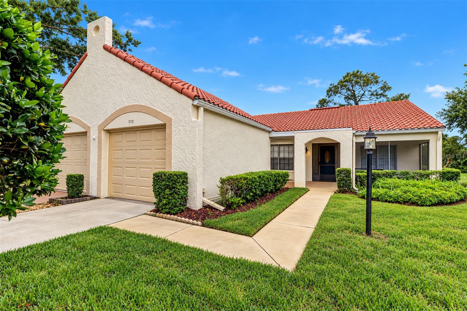 Meticulously maintained Mediterranean style 2 bedroom 2 bath villa with a tile roof, a one car garage, and located on the golf path and adjacent golf tee; a covered open 12 foot breezeway from the pedestrian garage door to front screened porch and into villa front door; extra patio/outside area in front of the garage off breezeway and a generous area in the rear of the villa to enlarge a more spacious patio area.  This light, bright and open split bedroom floor plan features separate dining and living rooms, fully equipped updated kitchen with cream cabinets and matching flat surface stove/range, built-in microwave, top freezer and bottom refrigerator, dishwasher and disposal.  Speckled cream, taupe and grey corian kitchen counter tops with integrated oversized double sinks.  Small eat in kitchen area and small closet pantry.  Kitchen has opening to living room and dining rooms on opposite ends of the kitchen. Extra bonus area at the end/rear of the living room that could be utilized as an office.  Living room has dry bar with lower cabinet and mirrored shelving from the cabinet top to ceiling; small coat closet just off the living room in hallway. Built in storage cabinet behind pony wall at the far end kitchen/living room opening adjacent to laundry closet for extra storage; rear pedestrian door off bonus area to the backyard patio on the golf path and golf course.  Primary bedroom is 14x12 with en-suite featuring double vanity and double sinks plus drawers together with tiled walk-in shower and large walk-in closet with shelving.  Second bedroom off front hallway is 12x10 with large walk-in closet; adjacent bath with tiled taupe tub/shower combination and single vanity.  Highland Lakes Master Association includes Highland Lakes Clubhouse, Arts and Crafts Annex Building, Highland Lakes Golf Club Building, Clubhouse Pavilion, Cabana Building and The Lake Tarpon Lodge.  There are 4 regulation tennis courts with night lighting, a 125,000 gallon Olympic sized pool with heated whirlpool spa; 45,000 gallon pool at the Lake Tarpon Lodge, 8 shuffleboard courts, 2 pontoon touring boats and the boat dock at Lake Tarpon Lodge, 3 nine-hole executive golf courses and bocce ball court.  The clubhouse and annex building have card rooms and meeting rooms, arts and crafts studios including a woodworking shop, ceramic studio and sewing studio.  You  can be as busy or as bored as you desire!  There is something for everyone in the active adult 55 plus community at Highland Lakes.  The community website is noted below to view all events and facilities.  All room sizes are deemed to be approximate.   The exterior photos were taken just moments before the torrential rain clouds opened up/our inclement daily weather has delayed the delivery of the interior photos for approximately a week.  Call for your private viewing today!