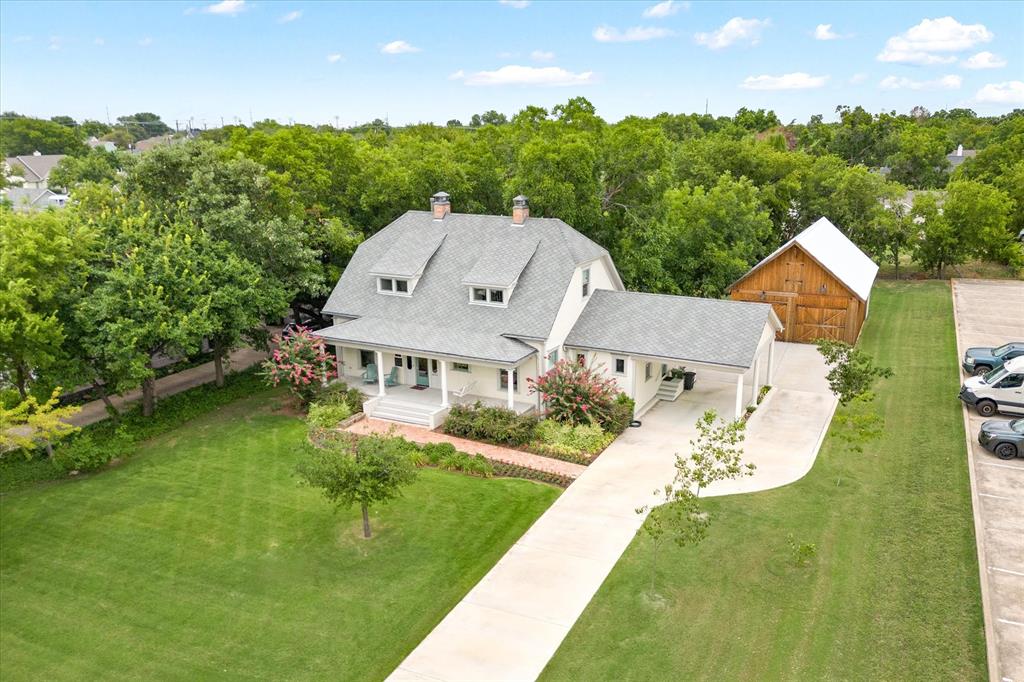 Located just minutes to the boat launches at Grapevine Lake, this home can house your boat, toys, workshop, workout room, or the collection of cars of every hobbyist's dream!  Check out the 4+ car barn with HVAC!  With walkability to downtown Grapevine to the restaurants, shops, and wineries, you're sure to love this location!  This historical home, known as the GE Hunt Home, was originally constructed in 1910 and rebuilt in 2016 through a meticulous renovation that preserved its soul while anchoring it in the now.  Set on a lush half-acre lot filled with mature native trees, this home feels like a page out of Grapevine’s past with a future-proof foundation, literally built atop a modern steel pier-and-beam system.  With over 4,500 square feet under roof and 2,780 square feet in the main home, the layout is as thoughtful as it is functional. Downstairs, the primary suite offers privacy and comfort with a spa-like ensuite bath, while a guest suite on the same floor provides hospitality with ease. A light-filled great room flows into the heart of the home—a luxurious kitchen with Thermador appliances and era-inspired cabinetry and color, plus and a dining area designed for gathering. Upstairs, two additional bedrooms each feature full baths, accompanied by a second living area and an expansive office space that could double as a creative studio or library.  The details tell the real story with preserved trimwork, hardwood floors, and antique-inspired fixtures which are all balanced by smart updates and energy-efficient systems. Outside, a 975 sq ft detached garage-workshop echoes the aesthetic of a classic Texas barn, offering functionality with curb appeal. And the porte-cochere near the mudroom and laundry isn’t just a design feature, it’s a daily convenience, enhanced by the Generac generator, ready on demand to power the home.  This is more than a historical home—it’s a legacy, lovingly restored and ready for its next chapter.