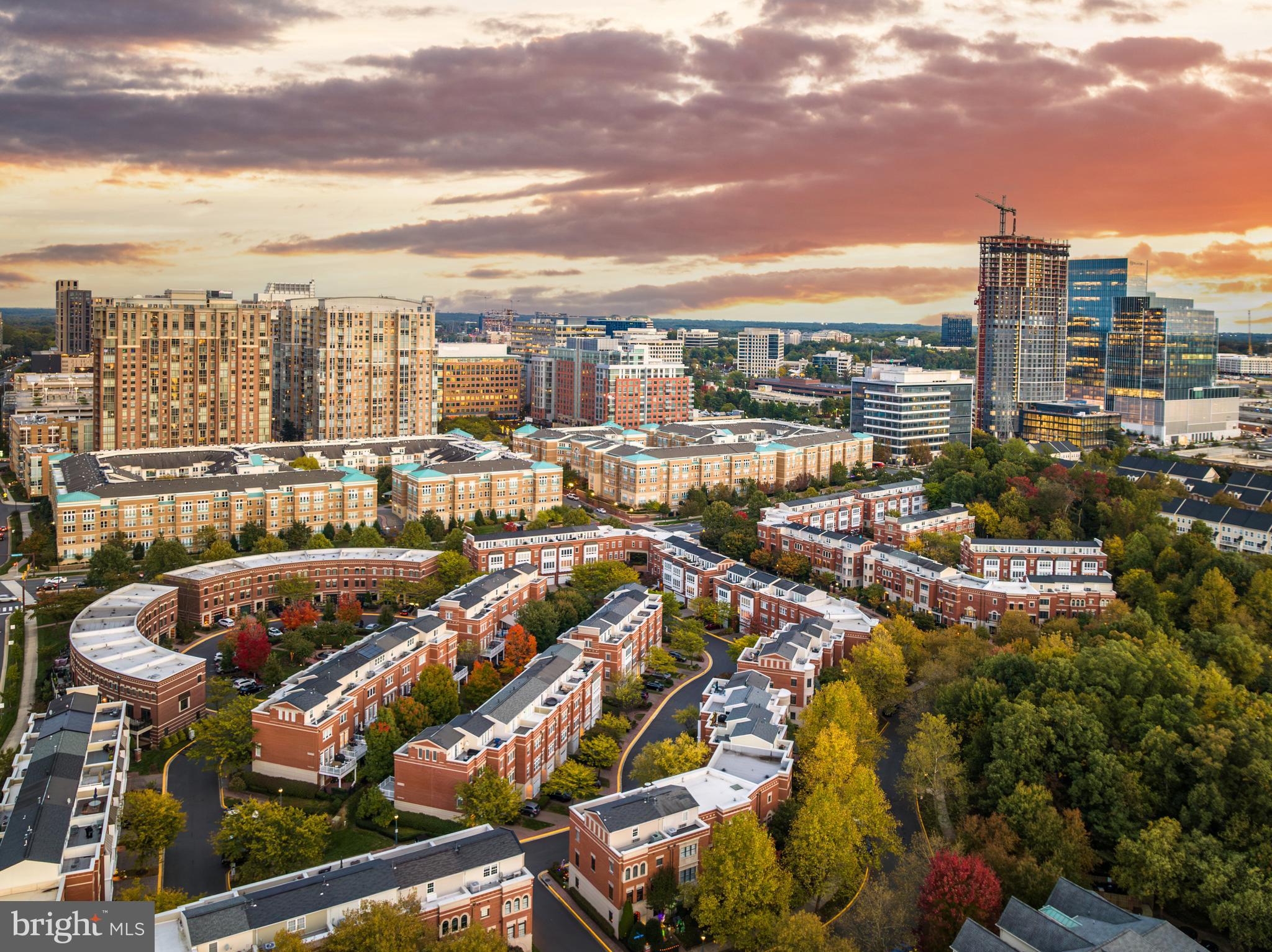 Welcome to 12147 Chancery Station in the highly desirable West Market neighborhood at Reston Town Center, a rarely available all brick Paris model townhome that lives beautifully across four finished levels with 2,128 square feet, three bedrooms, three full baths, and three separate outdoor spaces designed to be used and enjoyed. From the moment you step through the front door, you feel how well this home flows, with a first level that offers a full bath and flexible office, media room, or third bedroom, plus direct access to a slate patio and fully fenced landscaped garden that feels private and tucked away. Upstairs, the second level opens into a light filled layout where the kitchen, dining area, and family room connect seamlessly, anchored by a spacious kitchen with island and generous cabinetry, with easy access to a deck overlooking the garden and green space, making everyday living and entertaining feel natural and effortless. Hardwood flooring carries through the main living areas, adding warmth and continuity. The third level features two bedrooms with ensuite baths and walk in closets, including a primary suite with a custom built walk in shower, dual vanity, and two separate walk in closets with the laundry thoughtfully placed between the bedrooms for convenience. The fourth level loft is one of the true highlights of the home, complete with built ins, wet bar, cabinets, glass shelving, and a closet, creating a versatile space for entertaining, working from home, art, exercise, or simply relaxing, and it opens to a rooftop deck with panoramic views that truly elevate the entire experience. A one car garage includes a 240 volt outlet for EV charging. Gas line hookups are available on the kitchen deck for a grill or heater and on the fourth floor for potential future gas logs, and there is plenty of community guest parking nearby. Major improvements include Roof May 2021, HVAC May 2016, 4th Floor Wall Heating and Air Conditioning Unit October 2019, Hot Water Heater November 2015, Refrigerator September 2022, and a full replacement of the 4th floor utility deck liner, scupper, and exterior wall surfaces in September 2025 with a ten year warranty, offering confidence and peace of mind. Beyond the walls of the home, West Market combines true community with unbeatable convenience, with residents enjoying access to a private clubhouse, fitness center, patio, and swimming pool, all just steps from Reston Town Center where you can stroll to restaurants, retail, salons, fitness studios, personal services, public art, parks, free concerts, and year round events at the Pavilion. With the Silver Line Metro within walking distance, along with easy access to the Dulles Toll Road, Route 7, Fairfax County Parkway, and Dulles International Airport, commuting is simple whether you work in the city or travel often. Everyday conveniences are right at your fingertips, including the brand new Whole Foods, Trader Joe’s, Wegmans, Target, and more within a short drive. When you want fresh air, you can bike the nearby W&OD Trail or explore over 55 miles of Reston Association paved paths. This home offers an elevated lifestyle where location and design come together seamlessly, giving you the ability to walk to Metro, enjoy miles of trails, and be immersed in one of Northern Virginia’s most vibrant communities while coming home to a thoughtfully updated residence that truly stands out.