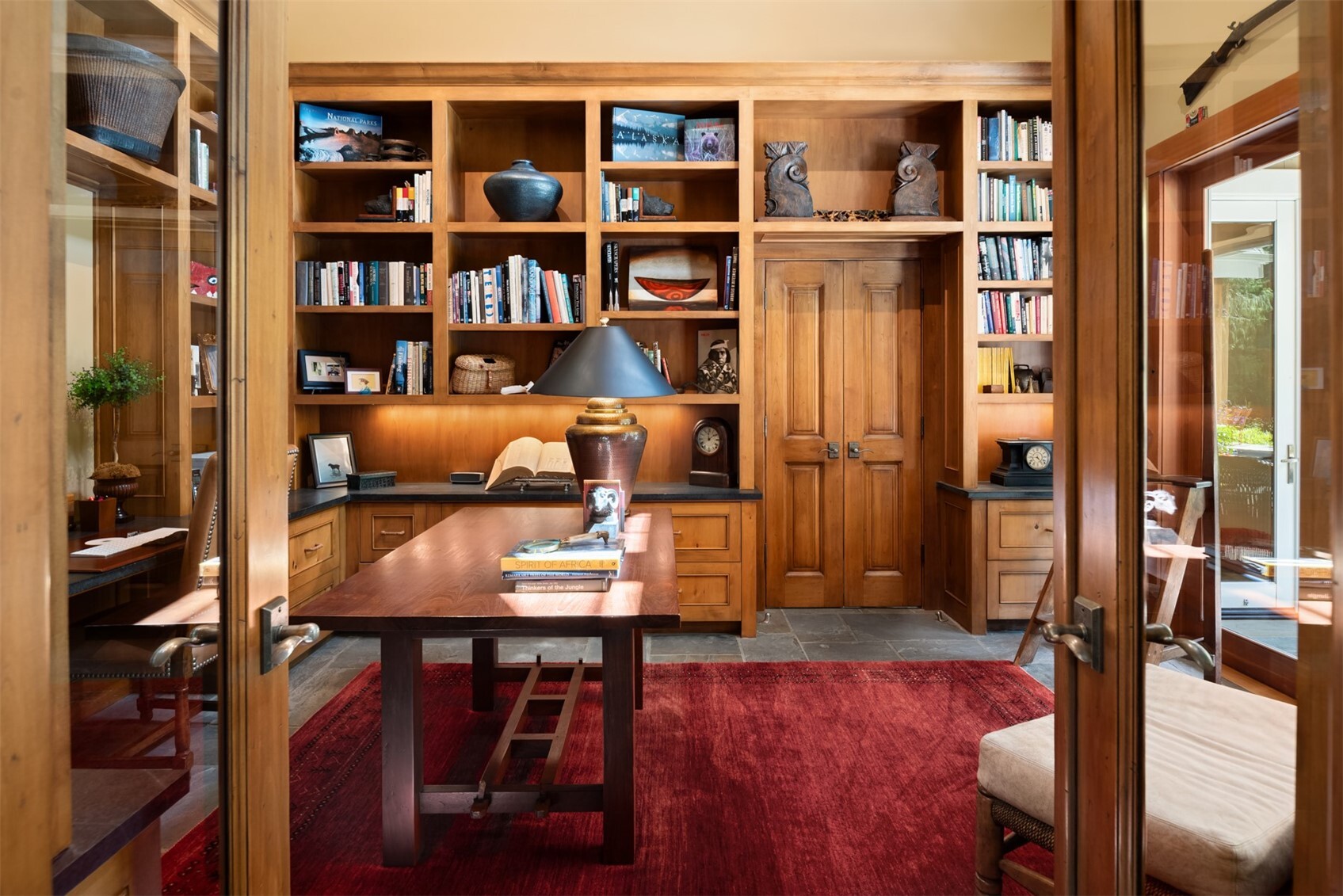 Home office with built-in bookshelves and red area rug