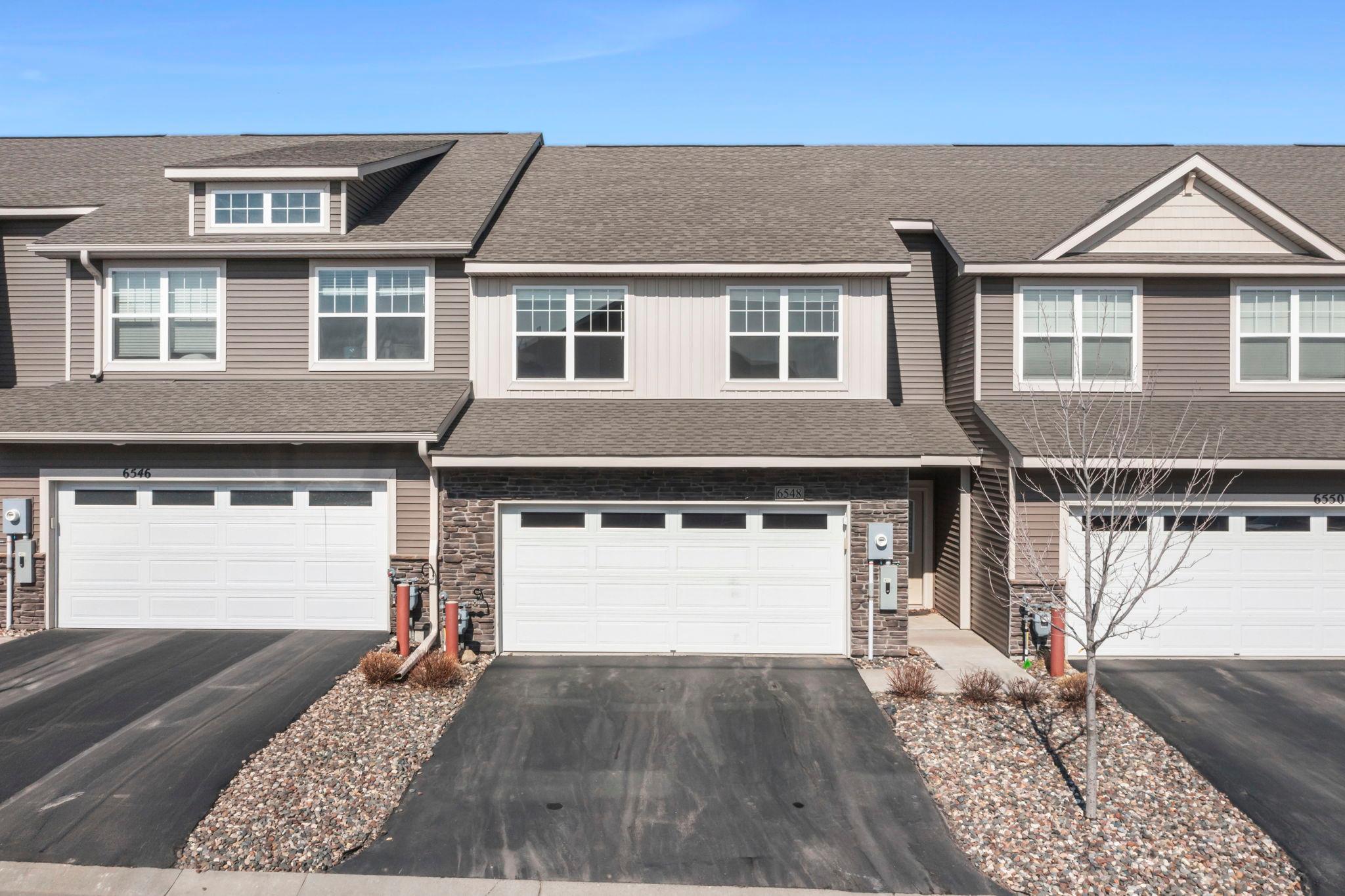 Welcome to this charming 3-bedroom, 3-bathroom townhome built in 2021! Ideally located within walking distance to Oltman Middle School and just minutes from Peter Thompson Park, this home also offers convenient access to Highway 10, along with nearby dining, shopping, and other local amenities. Enjoy maintenance-free living with lawn care, snow removal, and trash service all included. Step inside to a spacious living room with luxury plank flooring, a cozy electric fireplace, and recessed lighting. The kitchen boasts crisp white cabinetry, granite countertops, stainless steel appliances, and a large center island with breakfast bar seating. Just off the kitchen, the informal dining area features large windows with backyard views and access to the covered patio—perfect for indoor-outdoor entertaining. The main level also offers a half bath and attached two-car garage. Upstairs, the primary suite includes a private deck, ¾ bath with dual sinks, walk-in shower, and walk-in closet. Two additional bedrooms share a full bath with dual sinks and tub/shower combo. The upper level also offers a laundry room with Samsung washer and dryer, shelving, and a bonus room ideal for a home office or extra living space. Don’t miss this stunning home in a sought-after Cottage Grove location!