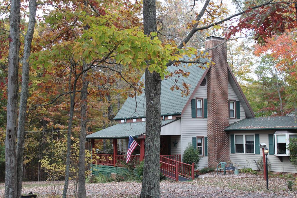 CHARMING AND COZY COTTAGE nestled in the woods with loads of character. This neat home features a roomy kitchen with cherry wood cabinets, brick firepace with gas logs, central vacuum system, gas furnace, sturdy construction, many interesting species of wood used throughout the house including locust, cherry, maple and pine to name a few. Walk out basement level features a full bath, utility room and living area with woodstove. Two full baths, bedroom, study, lots of storage space, and laundry are located on the main floor. Second level has the primary suite with walk in closets, and bath with jacuzzi tub. Attic for storage wiith fan. Relaxing front porch, split rail fencing, nice landscaping and large detached garage are just a few of the amenities this property offers. Great location just minutes from the Blue Ridge Parkway, the music center, and the towns of Galax and Sparta.