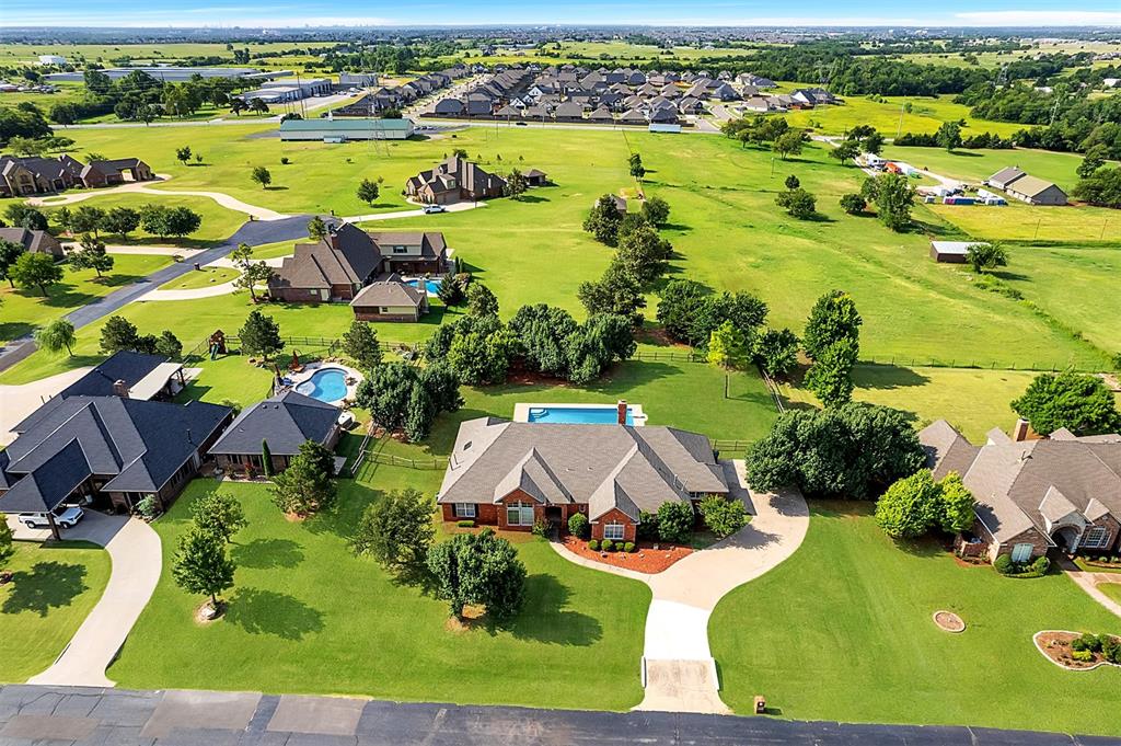 Experience luxury and space in the gated Deer Creek Hills neighborhood! Perfectly positioned on a generous .71 acre lot, this elegant estate offers peaceful rural living just minutes from the city. From the moment you arrive, you'll be captivated by the curb appeal with maintained flower beds, lush shrubs, and fresh mulch framed by the classic red brick exterior. Step through French doors into a foyer, and you'll immediately notice the warm, inviting atmosphere. To the left, you'll find a spacious formal living area and a refined dining room, both adorned with rich hardwood floors. Just beyond, the home opens up to a stunning open-concept kitchen, dining & living room flooded with natural light from expansive windows. The living area features custom woodwork framing a wood-burning fireplace, while the kitchen shines with granite countertops, plenty of cabinetry, built-in 5-burner gas cooktop, all-new stainless steel appliances (2018), black hardware, and crown molding. Updated lighting and hardwood floors run seamlessly throughout the main living spaces. The primary suite is a retreat with private patio access, views of the pool, and an ensuite bath that boasts a jetted tub, double vanities, stall shower with obscure glass doors, and a walk-in closet. Three additional bedrooms all offer spacious walk-in closets, large windows with blinds, and share two beautifully maintained bathrooms, one with a dual-sink vanity, the other with plenty of counter space and both featuring tub/shower combos. A well-equipped laundry room includes ample counter space, cabinets & a sink. Step outside to your private oasis, complete with a modern built-in pool & diving board, oversized covered patio, and plenty of open space for entertaining. The new wood privacy fence, in-ground storm shelter, and large trees offer both comfort and peace of mind. Additional upgrades include both HVAC systems and ductwork replaced in 2016, each equipped with air purifiers for improved indoor air quality.