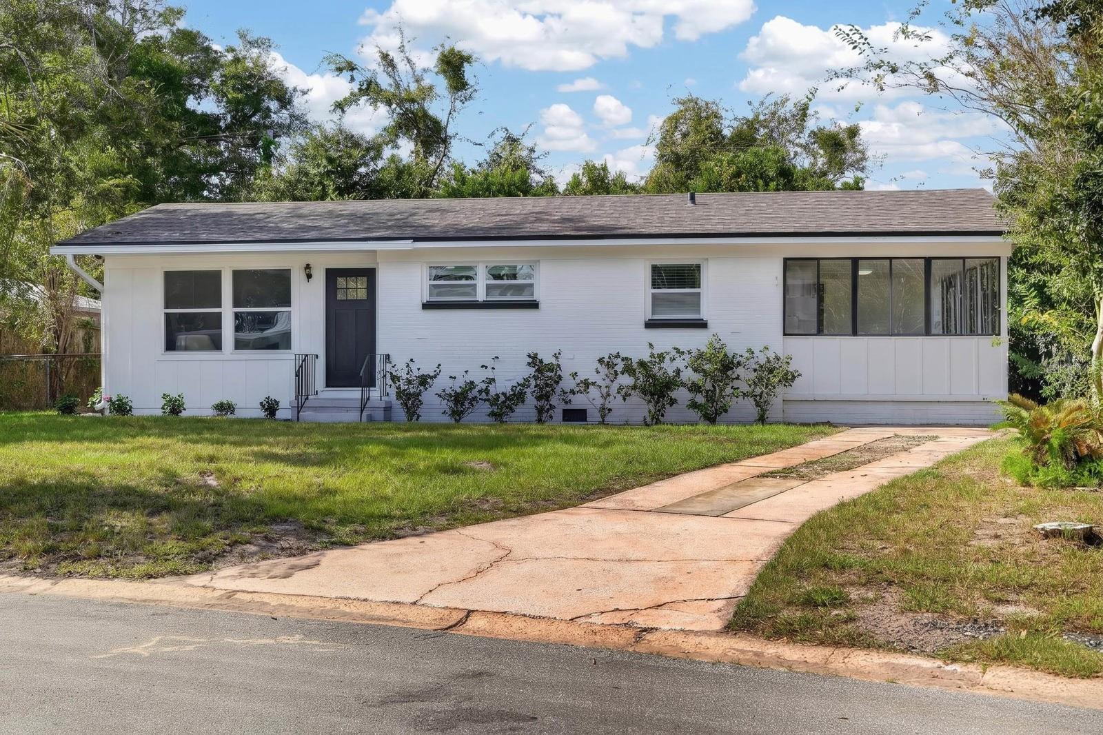 Welcome home to this renovated 3-bedroom, 1.5-bathroom brick ranch on a generous 0.26-acre lot in St. Augustine, Florida. Step inside to a bright living room where large windows fill the space with natural light, and a fresh neutral palette flows into a separate dining area made for shared meals. The galley kitchen is ready for everyday cooking, with white raised-panel cabinetry, granite countertops, stainless steel appliances including a French-door refrigerator, an undermount sink, a matte black pull-down faucet, and easy-care tile flooring. The enclosed Florida room, framed by a wall of black-framed windows and painted brick, is ideal for a home office, gym, or quiet morning coffee. Outside, white painted brick, board-and-batten accents, and a craftsman-style front door create inviting curb appeal. The large backyard offers mature shade trees and plenty of room for a garden or patio. Move-in ready, single-level living in St. Augustine close to downtown and 95 for easy access.